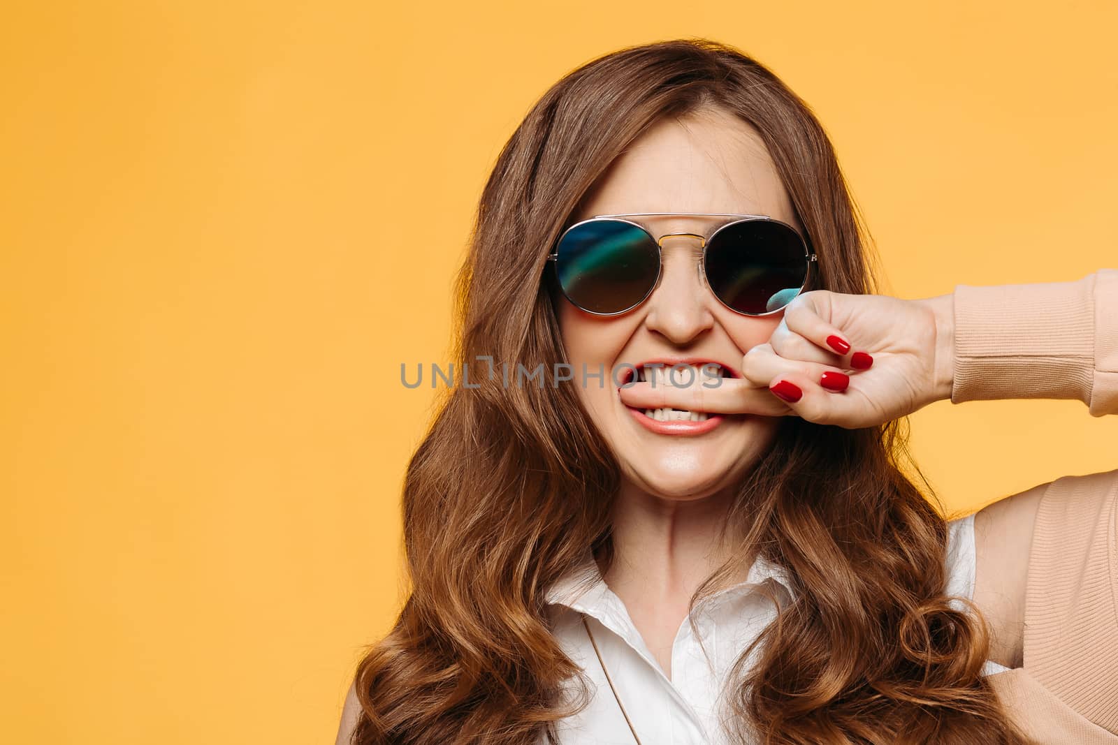 Stylish beautiful brunette woman with wavy hair, perfect make up after beauty salon,wearing in dress, posing with hand on waist, crossed legs. Beige studio background.Concept of shopping and fashion.