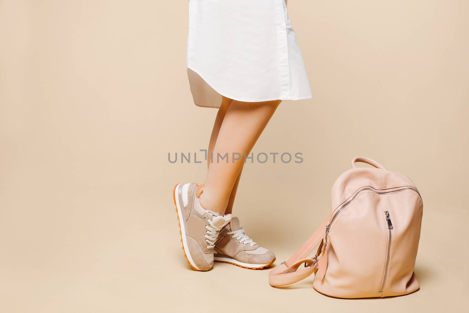 Stylish woman in fashionable beige dress standing near leather bag. by StudioLucky
