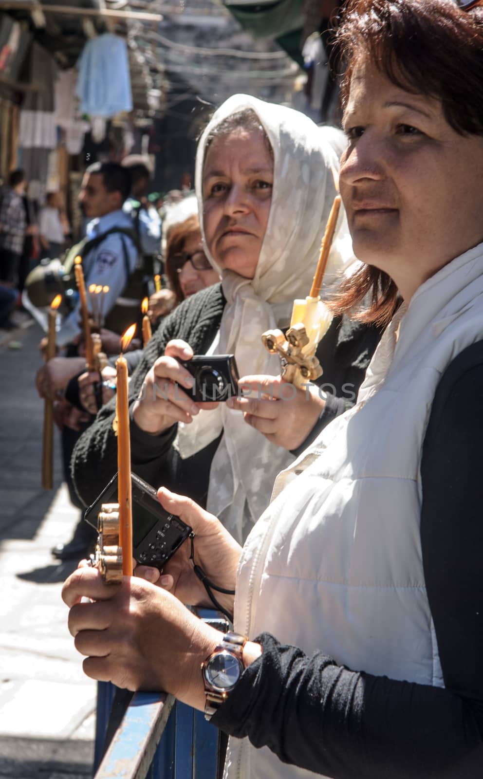 JERUSALEM - APRIL 18, 2014: A group of Pilgrims holding candles while watching the cross carrying ceremonies, along Via Dolorosa, on Good Friday, in the old city of Jerusalem, Israel