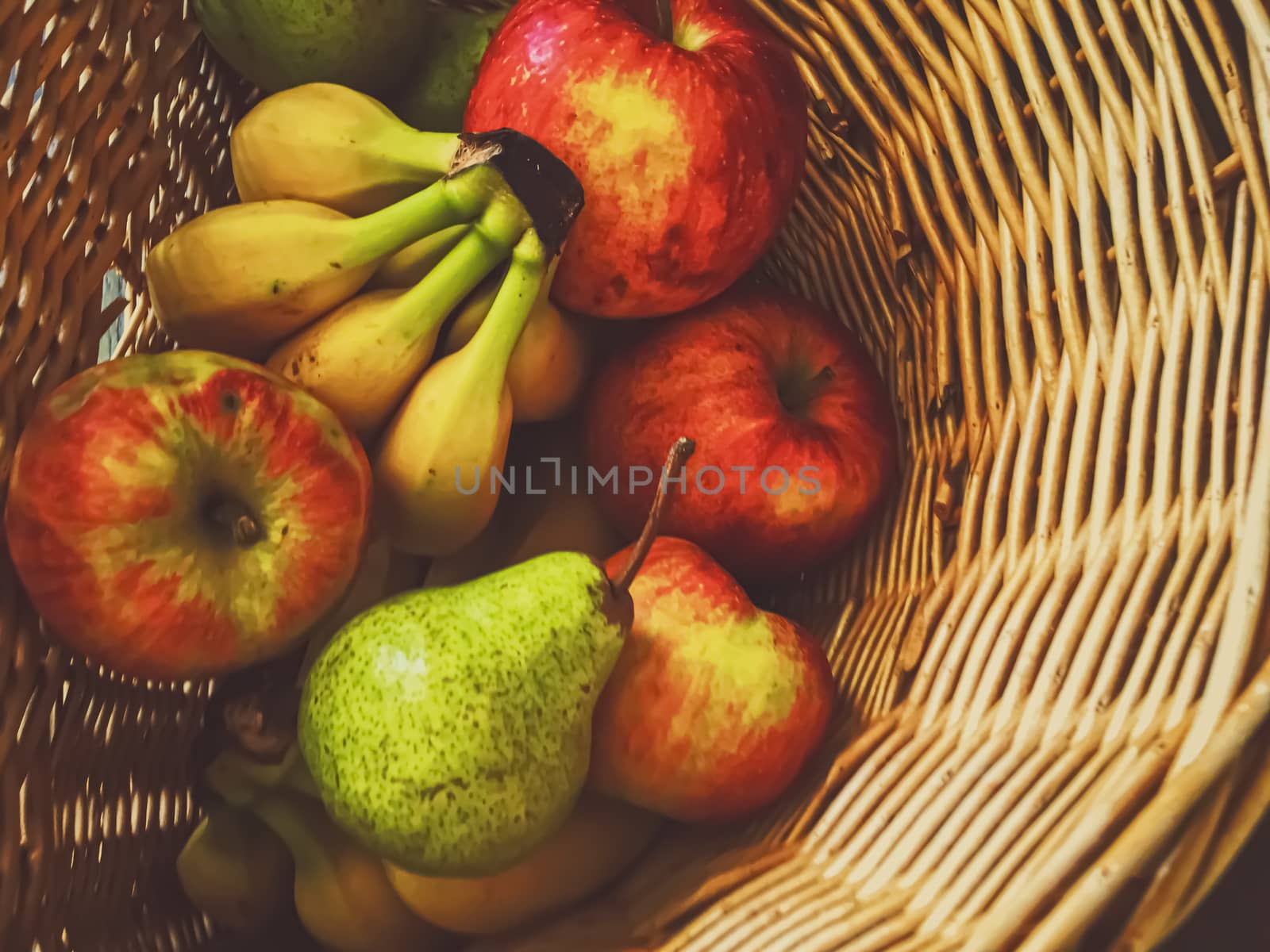 Organic apples, pears and bananas on rustic in a wicker basket, fruits farming and agriculture