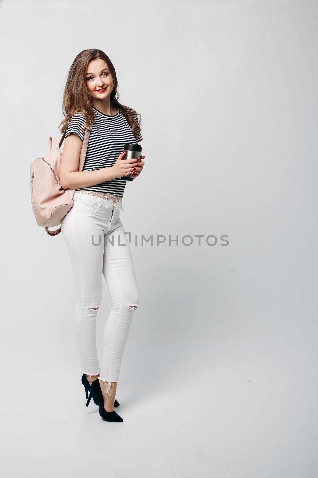 Stylish brunette girl holding thermos with warm coffee. by StudioLucky