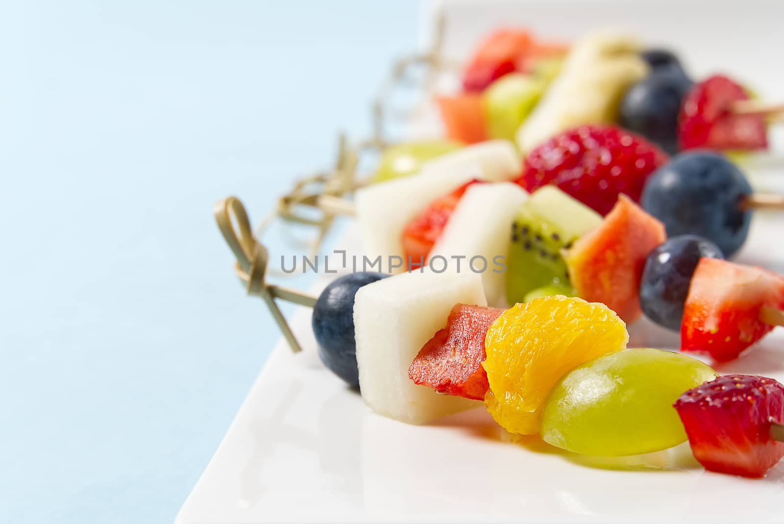 Fruit canapes. Fresh fruit canapes on white plate. Mixed fruit in white plate healthy food style, blue backgrounds. by PhotoTime