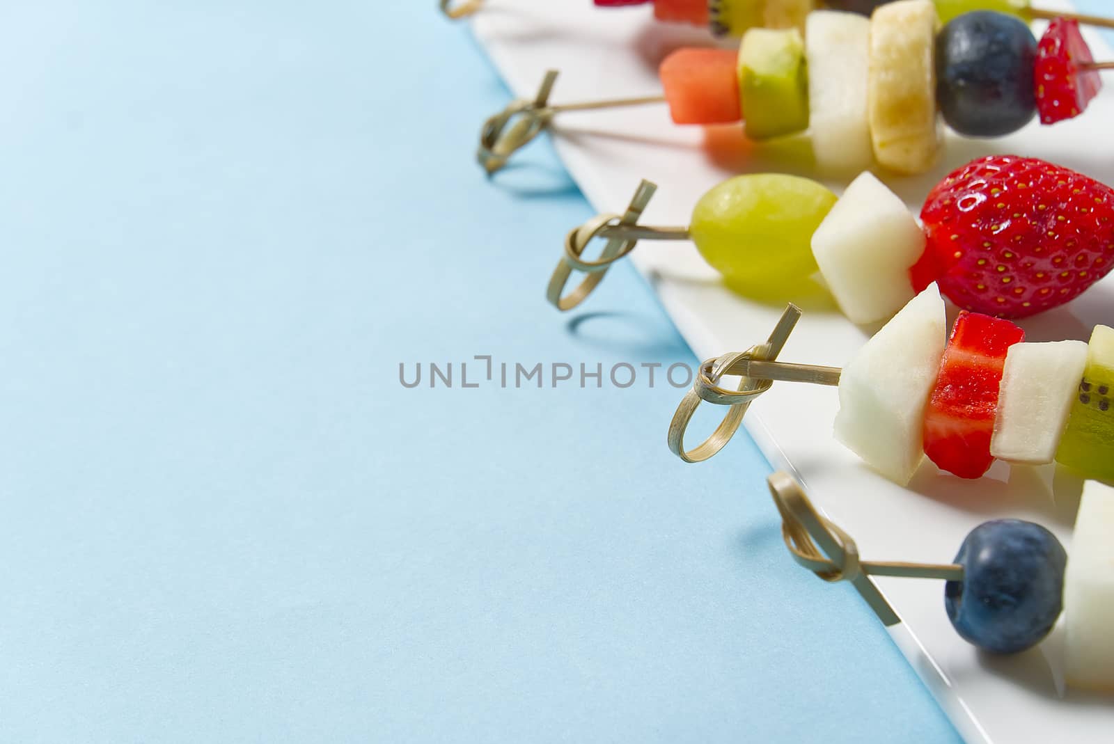 Fruit canapes. Fresh fruit canapes on white plate. Mixed fruit in white plate healthy food style, blue backgrounds