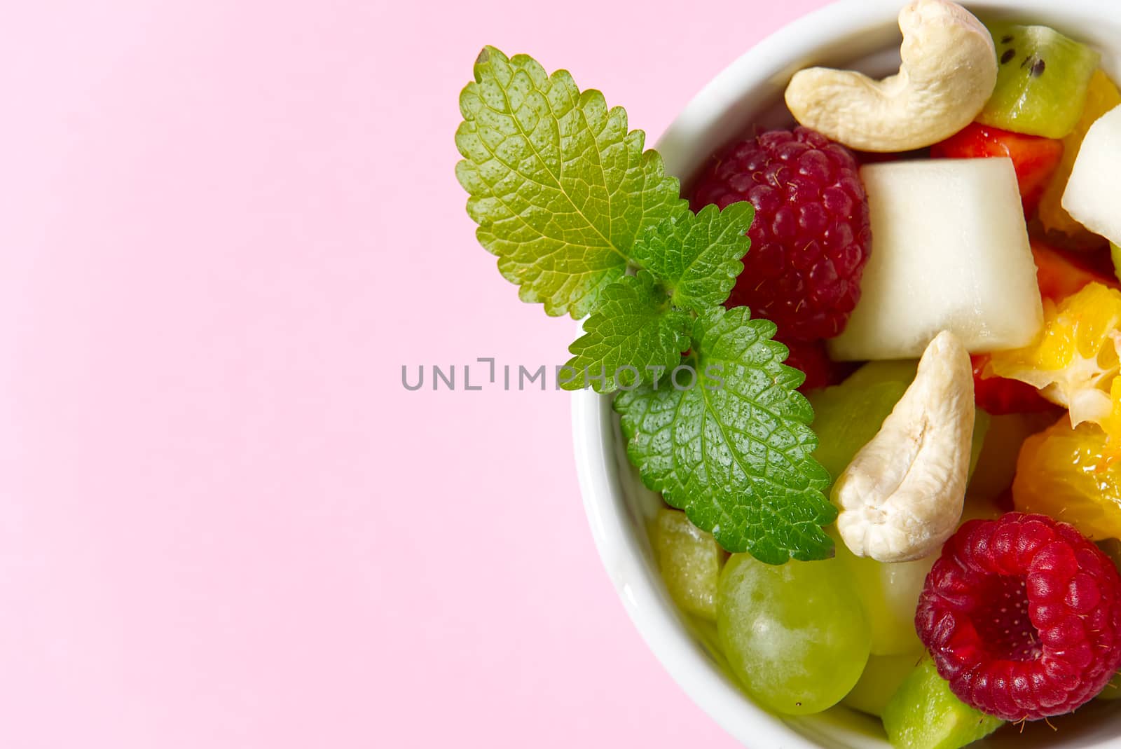 Three bowls with fruit salad. Fresh fruit salad on white bowl. Mixed fruit in white bowl healthy food style. Useful fruit salad of fresh fruits and berries on pink background.