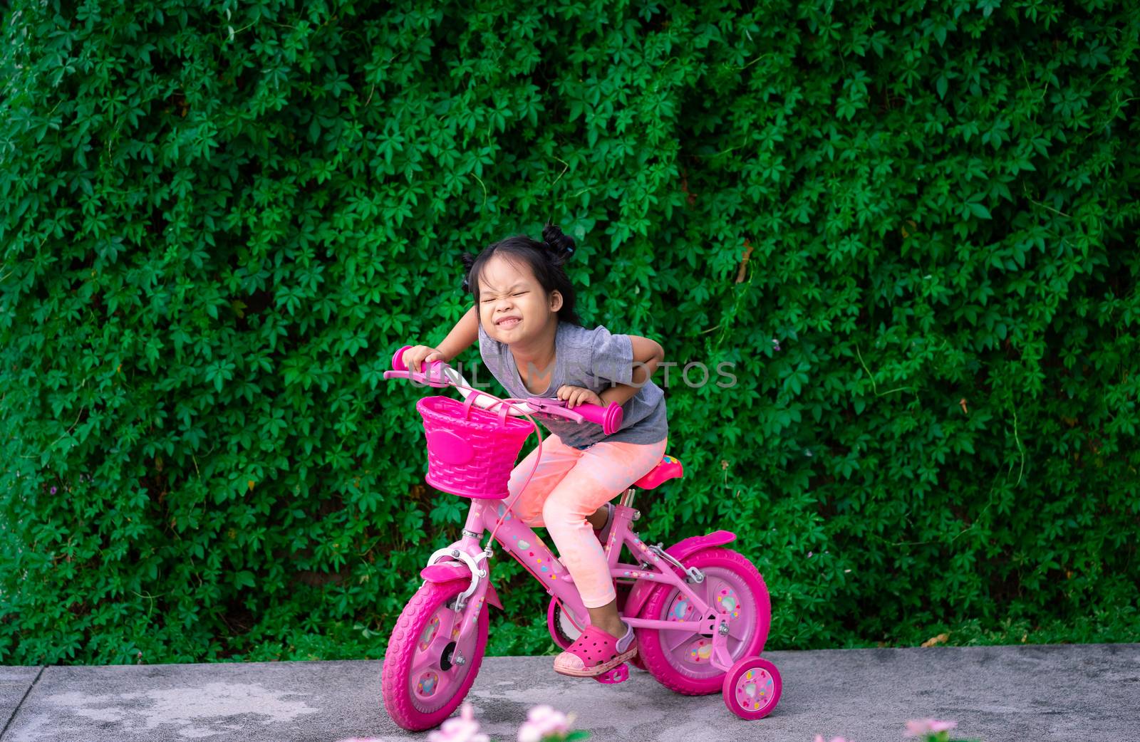 Cute little asian girl riding a bicycle to exercise in park, kids sport and active lifestyle