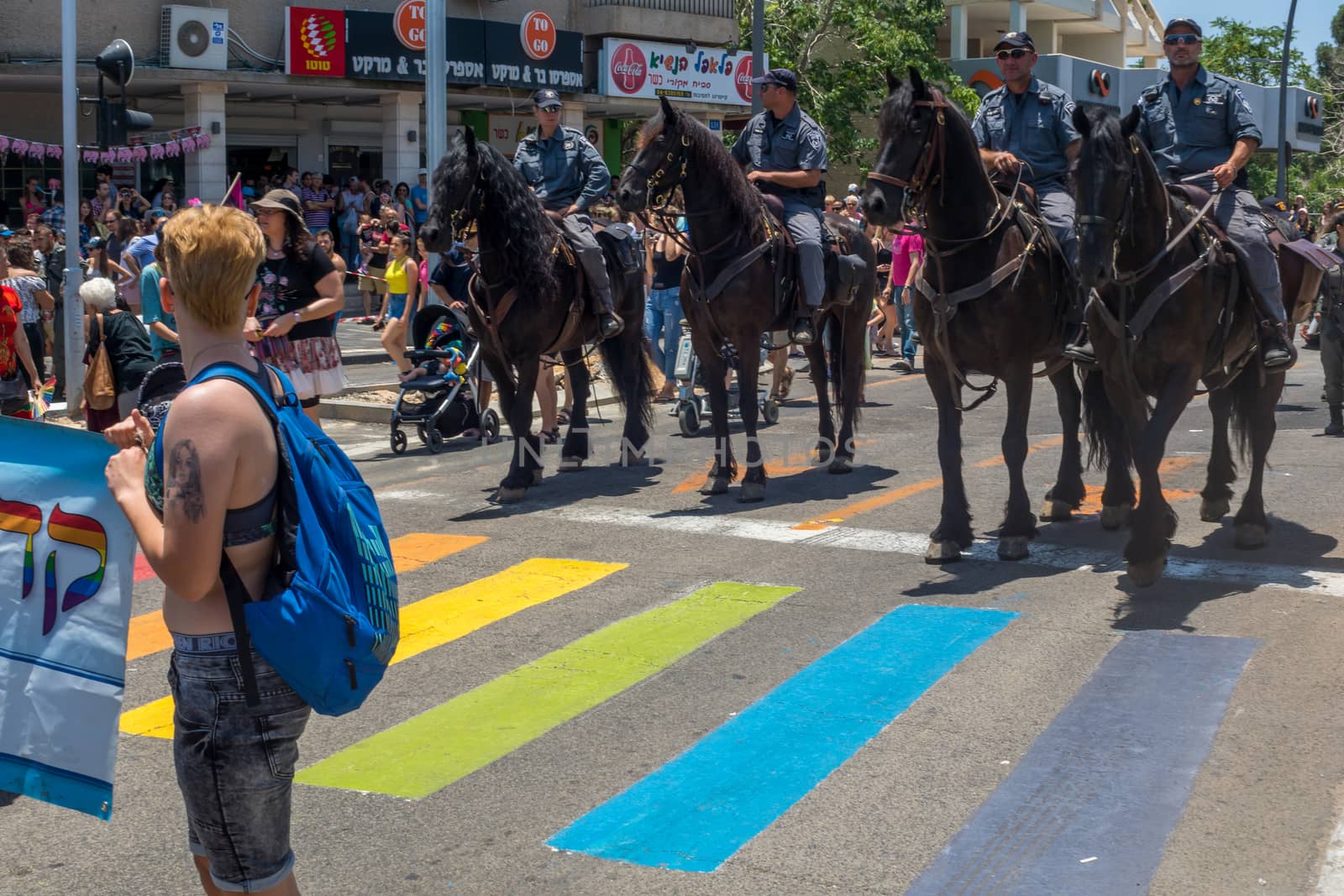 HAIFA, ISRAEL - JUNE 22, 2018: Zebra crossing painted in the rainbow colors, policemen on horses, and other participants, in the annual pride parade of the LGBT community, in Haifa, Israel