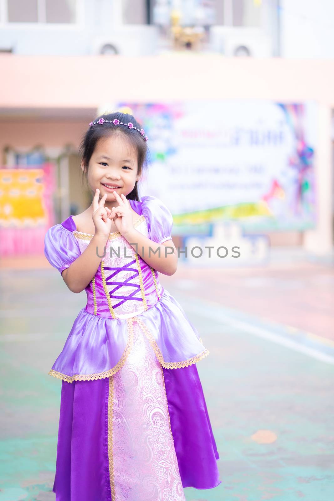 Portrait of cute smiling little girl in princess costume standing in school