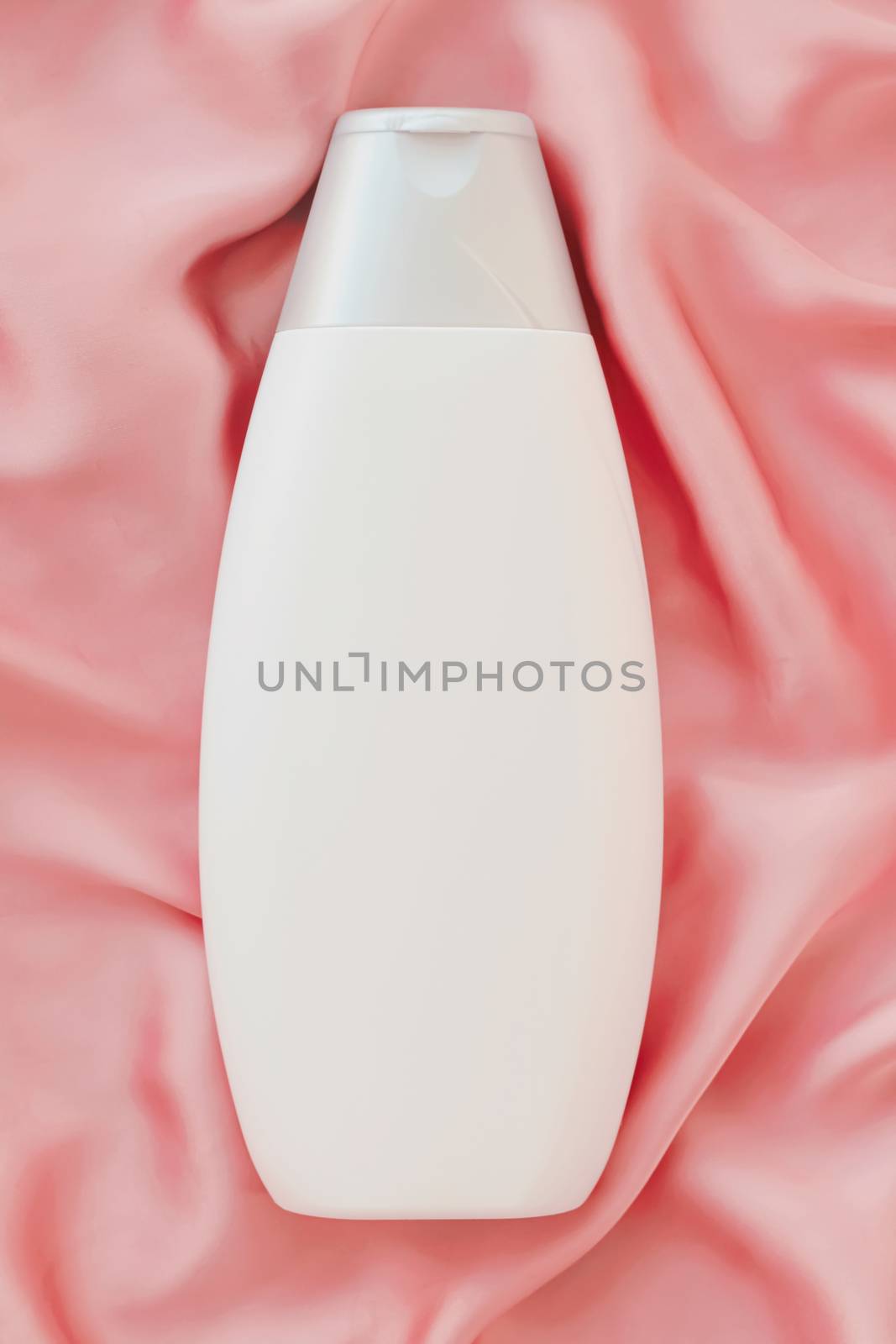 Blank label cosmetic container bottle as product mockup on pink silk background by Anneleven