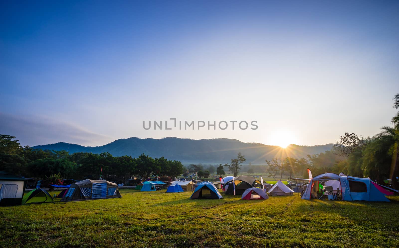 Camping and tent in nature park with sunrise behind the mountain