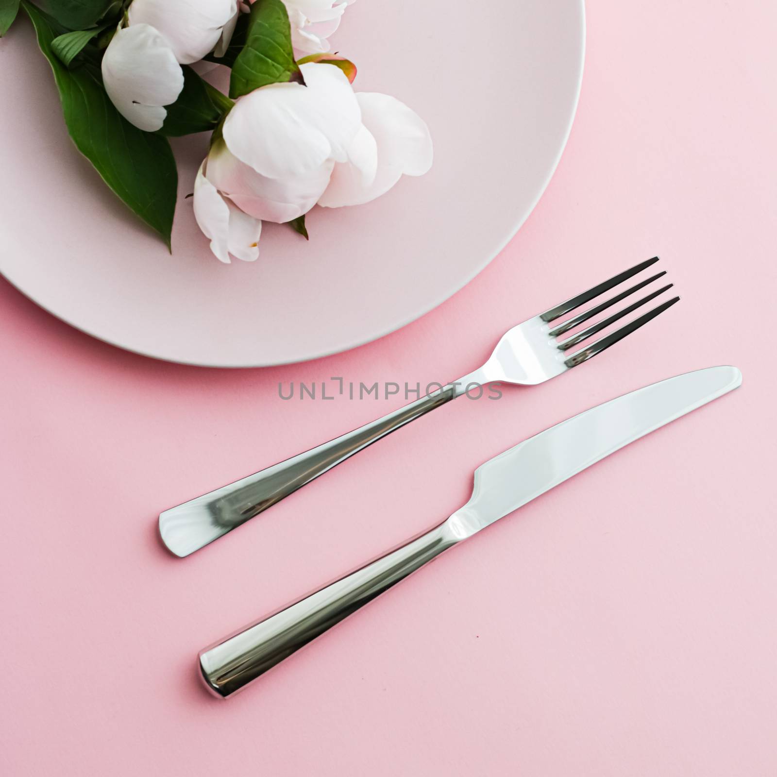 Dining plate and cutlery with peony flowers as wedding decor set on pink background, top tableware for event decoration and menu branding by Anneleven