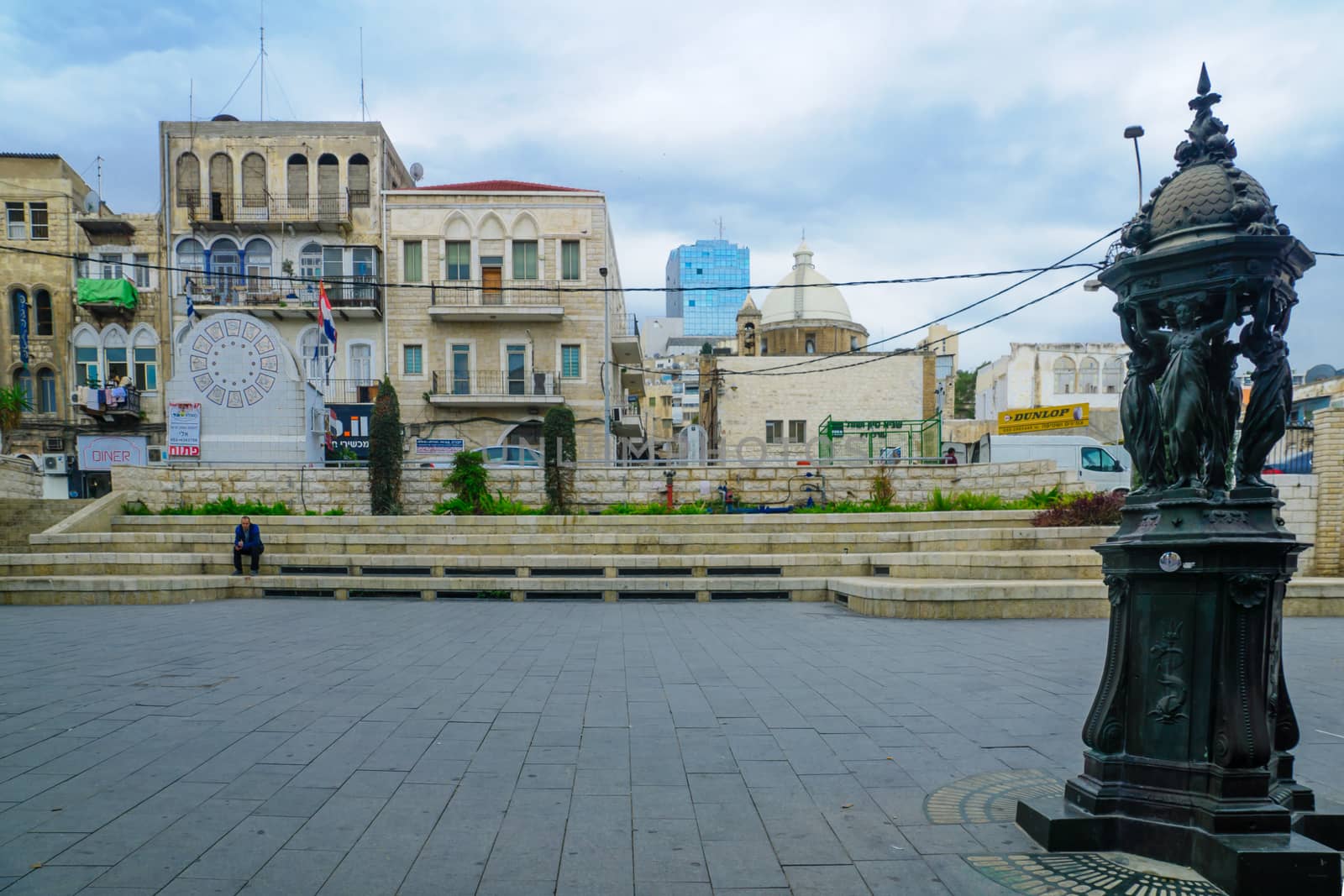 HAIFA, ISRAEL - DECEMBER 08, 2016: Scene of Paris square in downtown, with locals and visitors, the Maronite Cathedral of St. Louis the King, HaNeviim tower, and other buildings, in Haifa, Israel