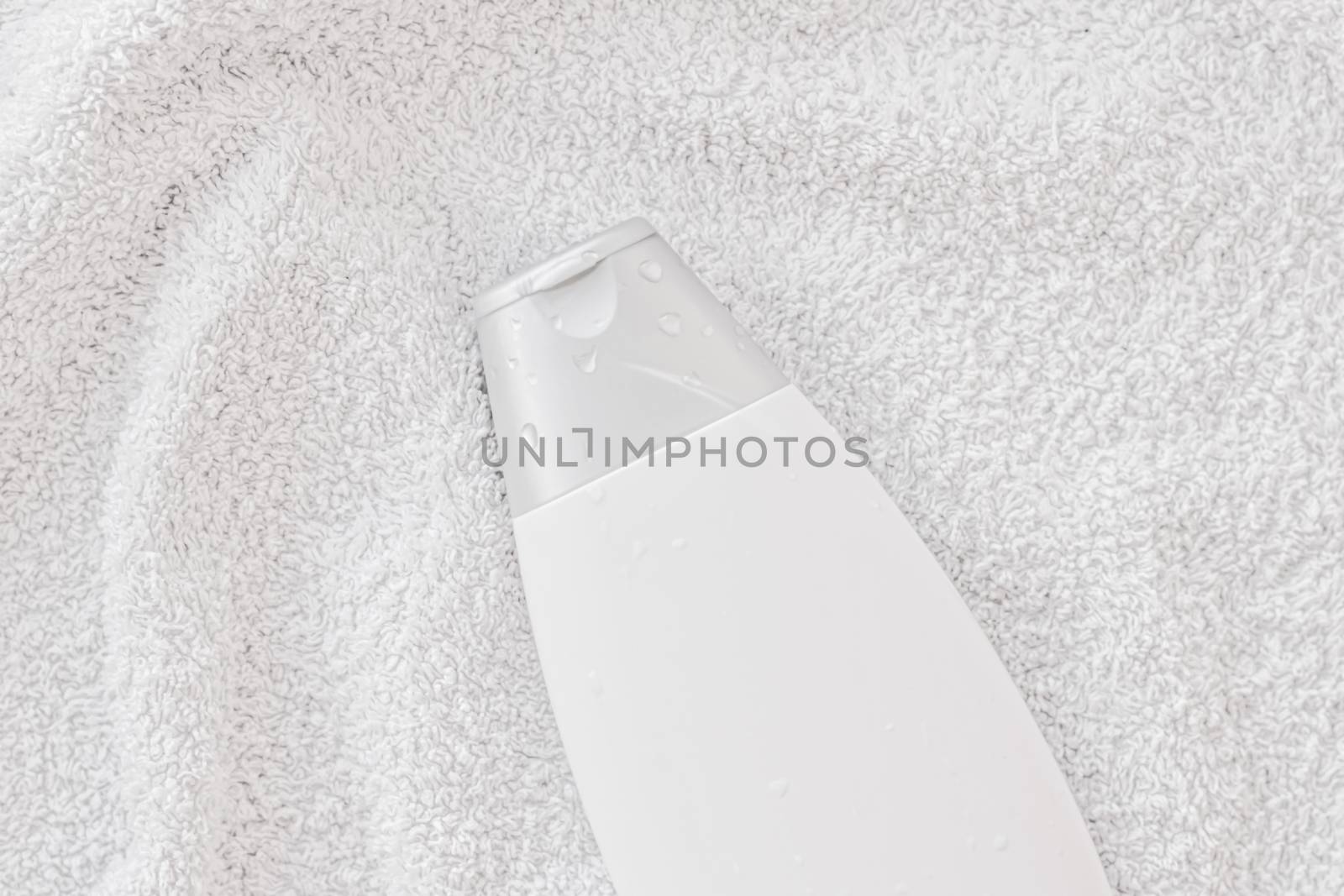 Blank label cosmetic container bottle as product mockup on white towel background by Anneleven