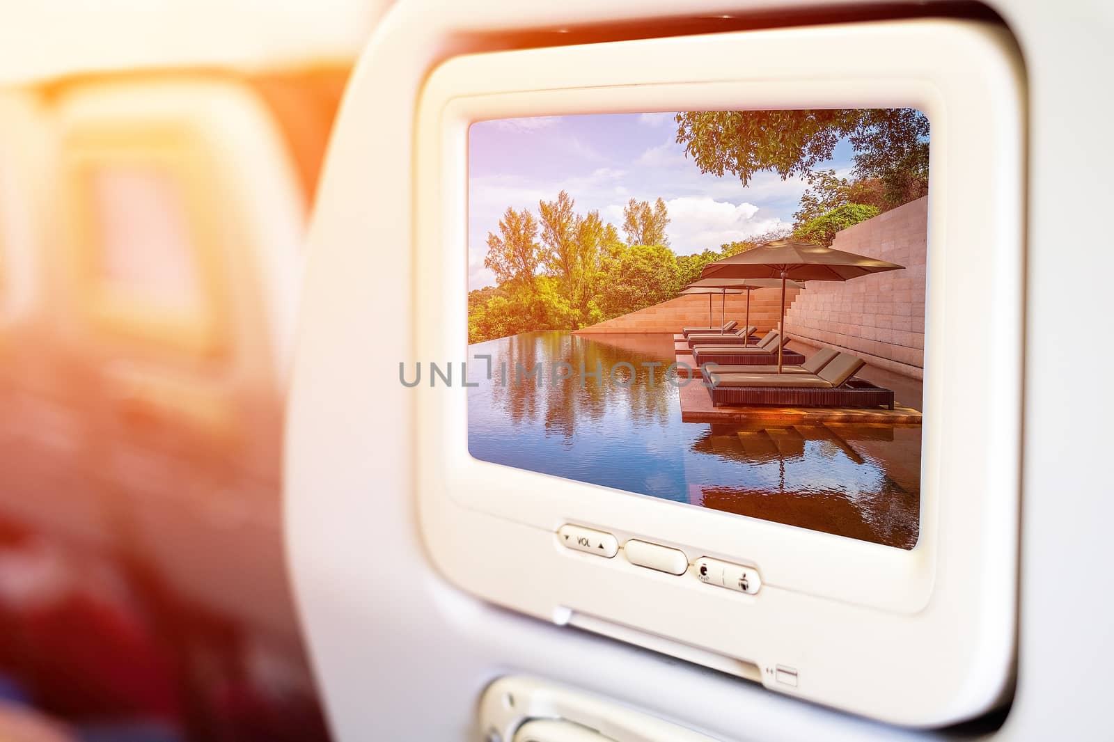 Aircraft monitor in passenger seat on beach pool background by Surasak