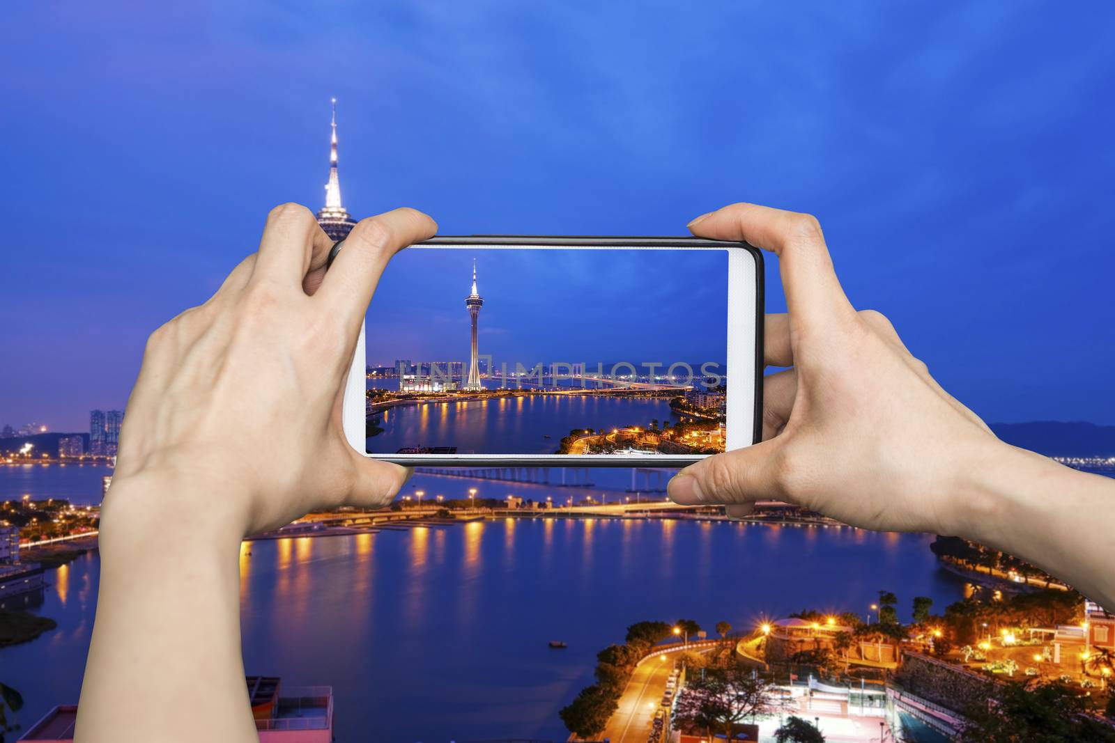 Taking pictures on mobile smart phone in Night view of Macau Tower in Twilight Time