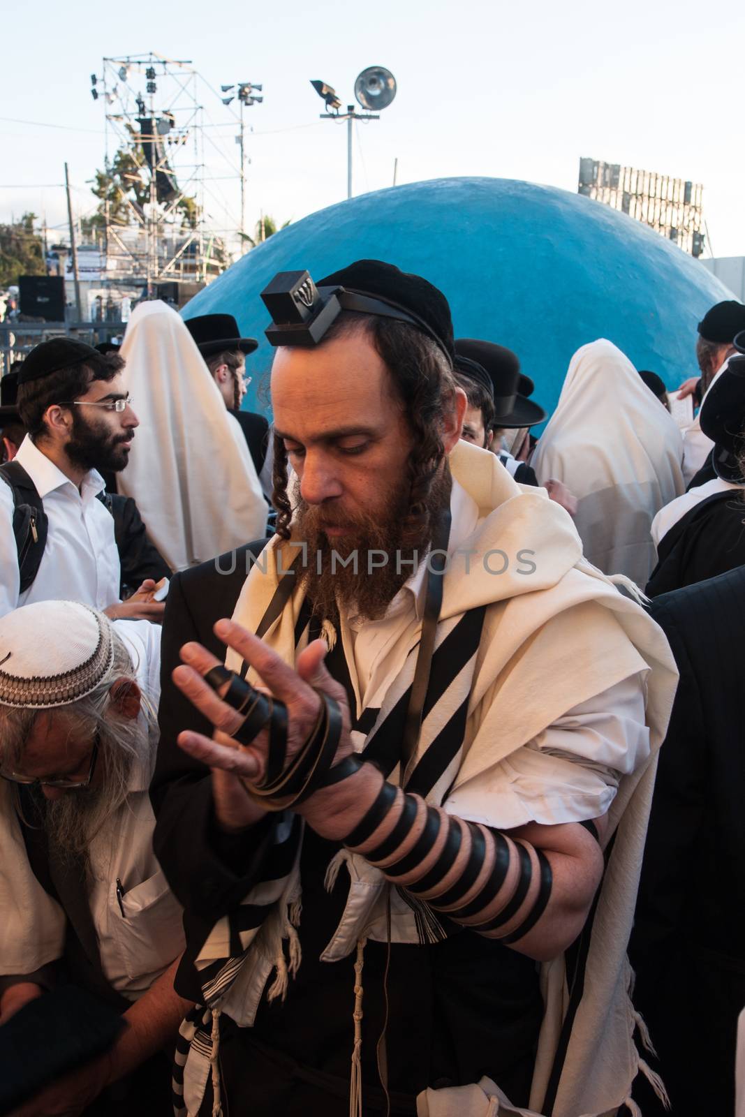 MERON, ISRAEL - MAY 18, 2014: An orthodox Jew putting on his tefillin, near the tomb of Rabbi Shimon, at the annual hillulah of Rabbi Shimon Bar Yochai, in Meron, on Lag BaOmer Holiday.