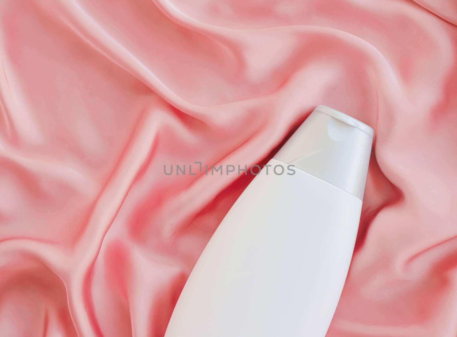 Blank label cosmetic container bottle as product mockup on pink silk background by Anneleven