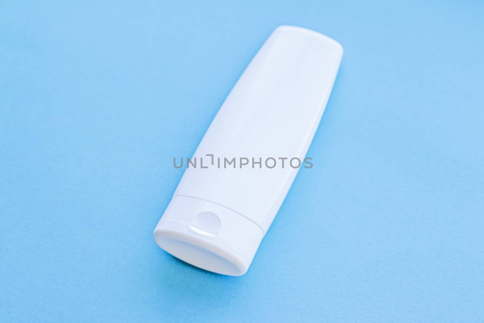 Blank label cosmetic container bottle as product mockup on blue background, hygiene and healthcare