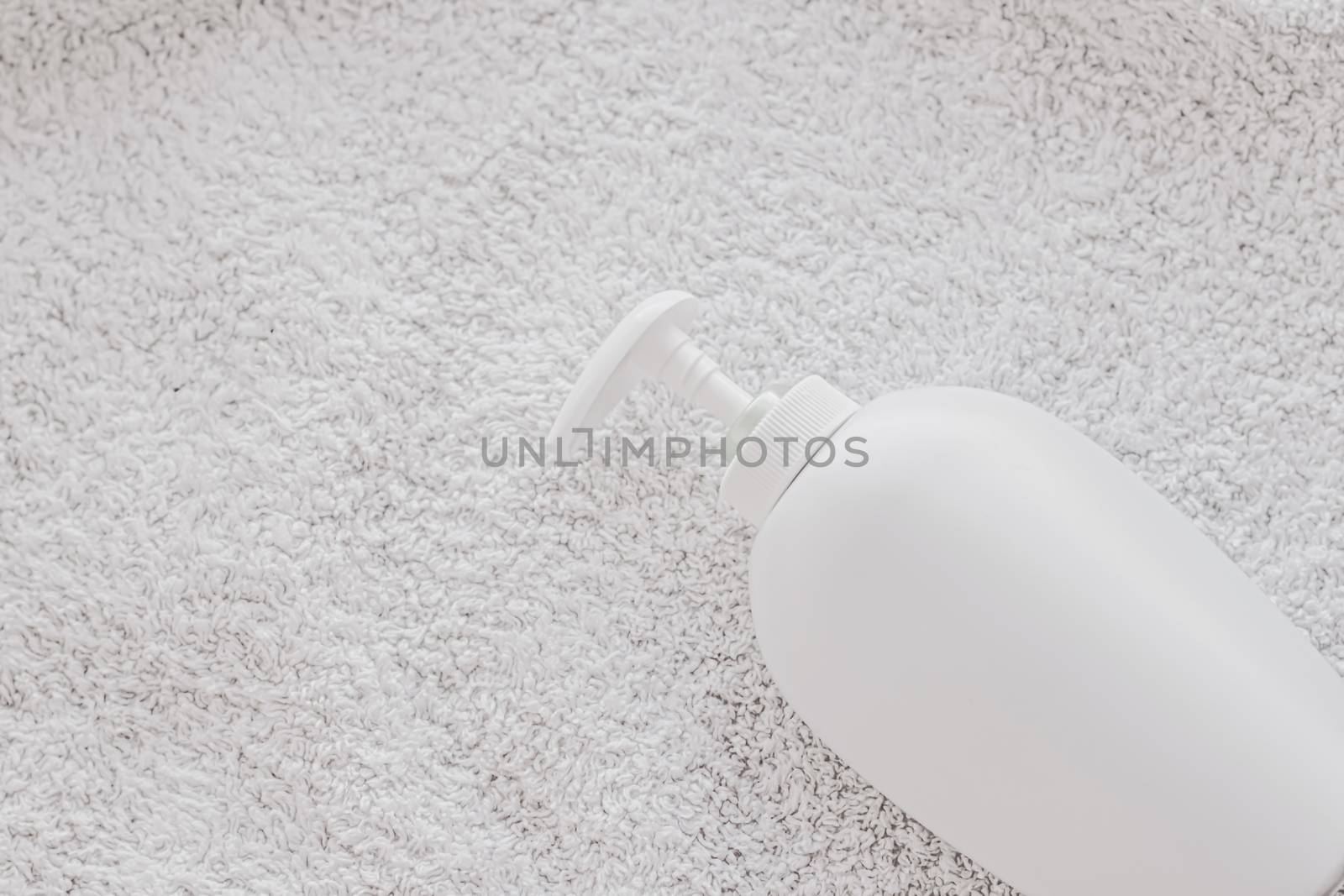 Blank label cosmetic container bottle as product mockup on white towel background by Anneleven