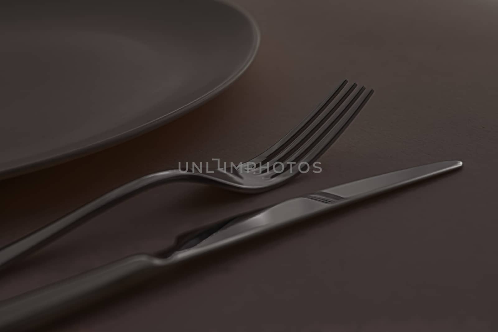 Empty plate and cutlery as mockup set on dark brown background, top tableware for chef table decor and menu branding by Anneleven