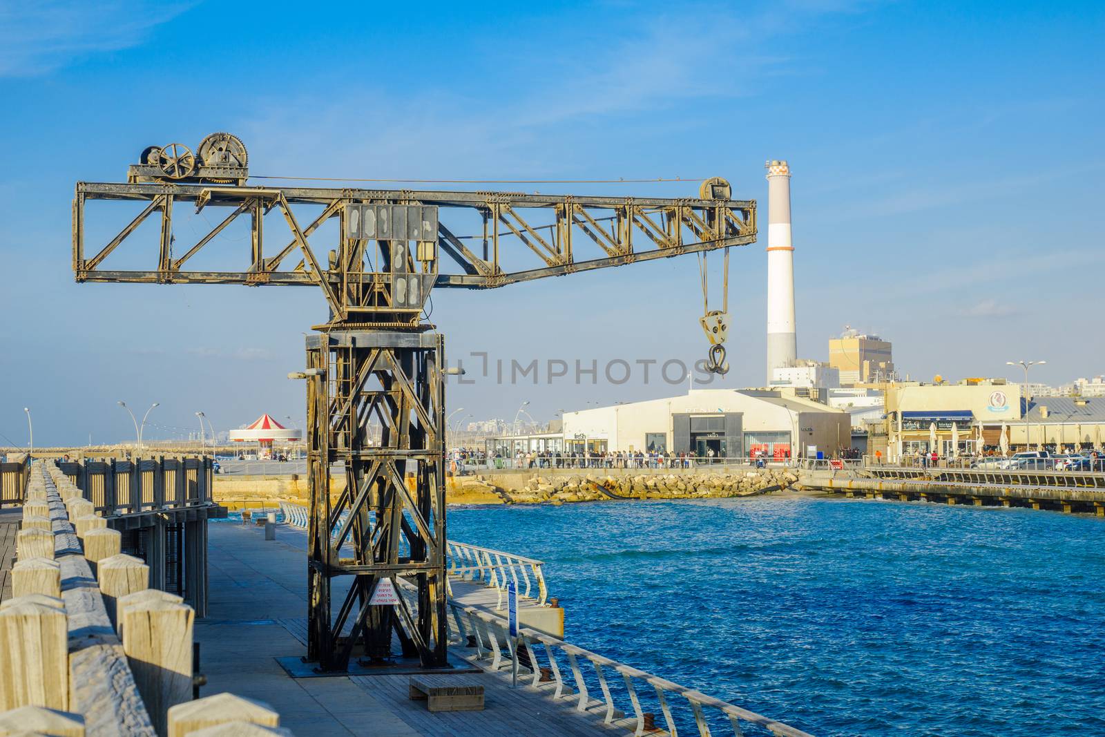 TEL-AVIV, ISRAEL - JANUARY 12, 2017: Scene with a restored crane, a carrousel, a commercial area, the Reading power station chimney, and visitors, in Tel-Aviv Port, Tel-Aviv, Israel