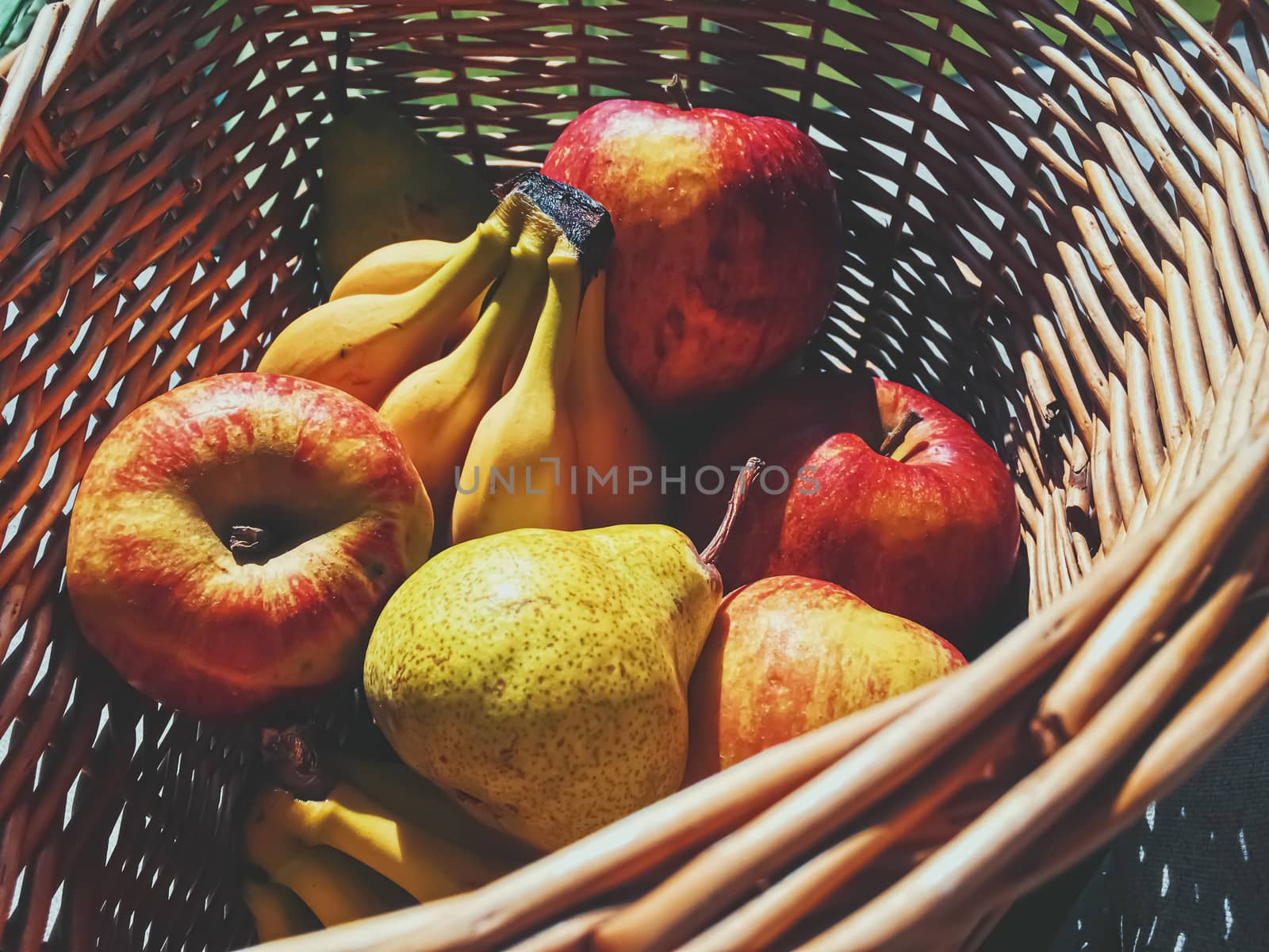 Organic apples, pears and bananas on rustic in a wicker basket, fruits farming and agriculture