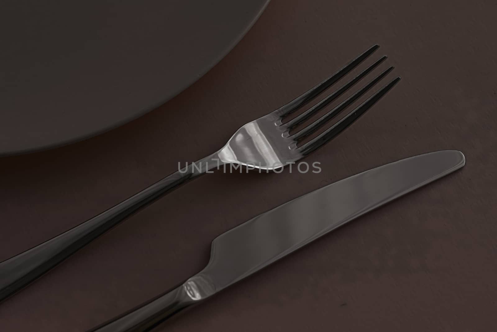 Empty plate and cutlery as mockup set on dark brown background, top tableware for chef table decor and menu branding design