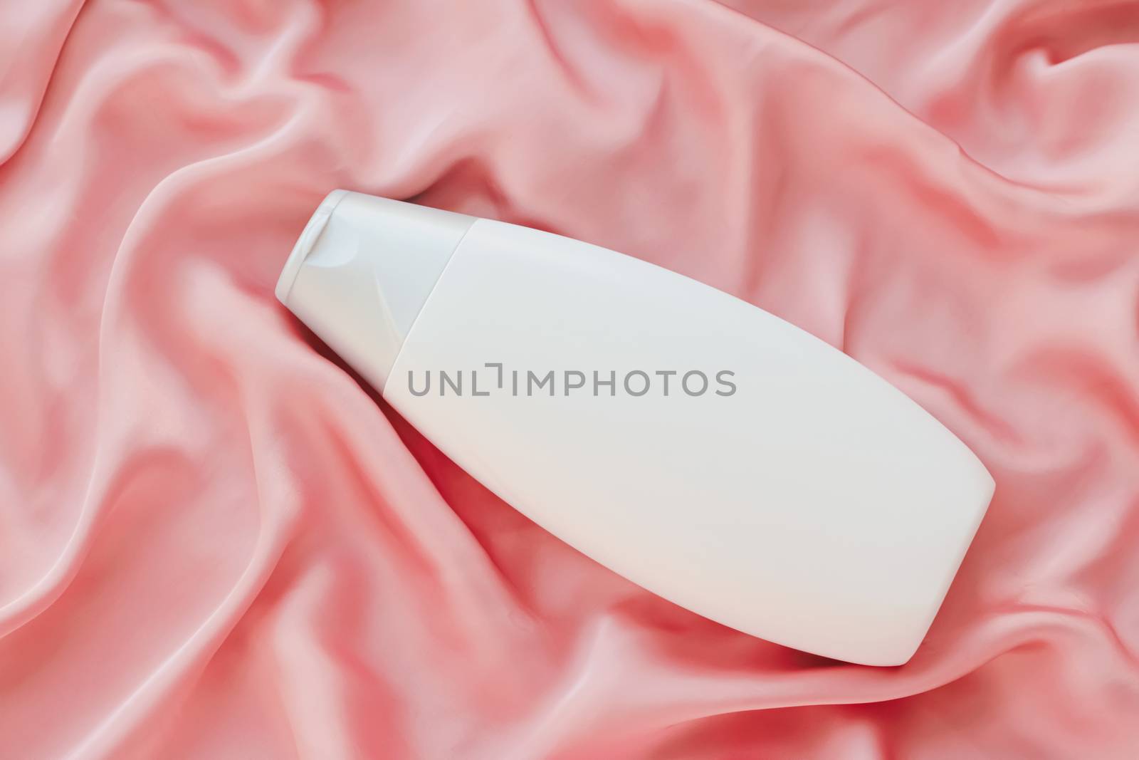 Blank label cosmetic container bottle as product mockup on pink silk background by Anneleven