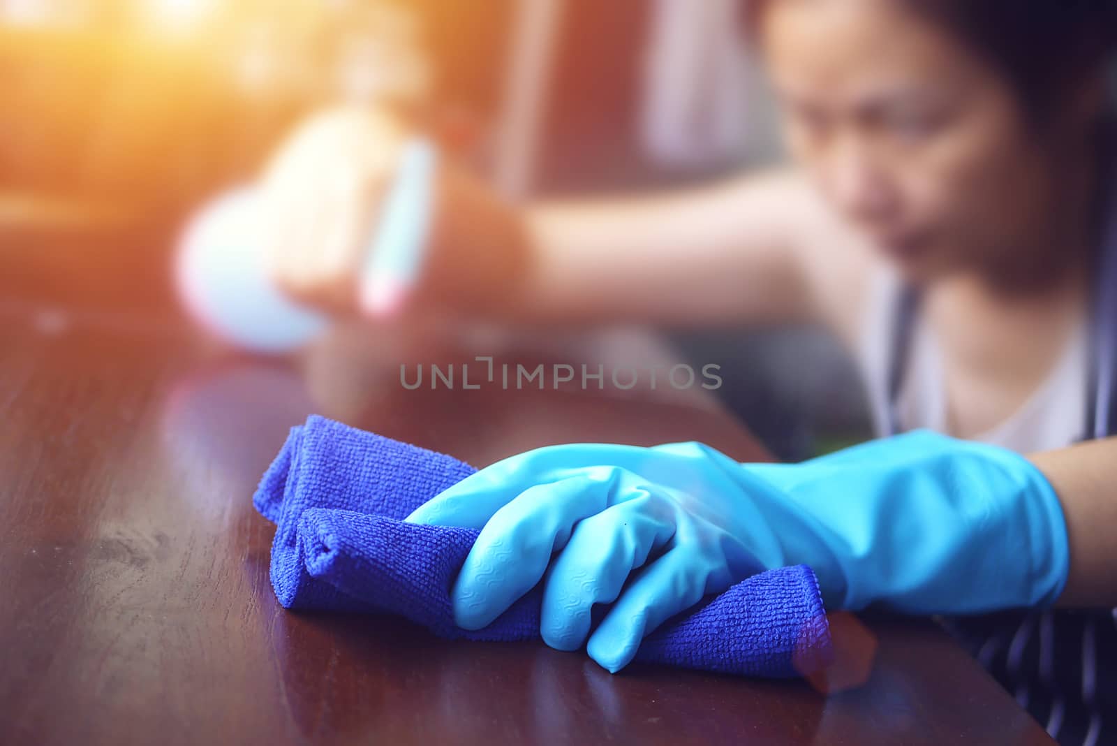 hand in blue rubber glove holding blue microfiber cleaning cloth and spray bottle with sterilizing solution make cleaning and disinfection for good hygiene by asiandelight