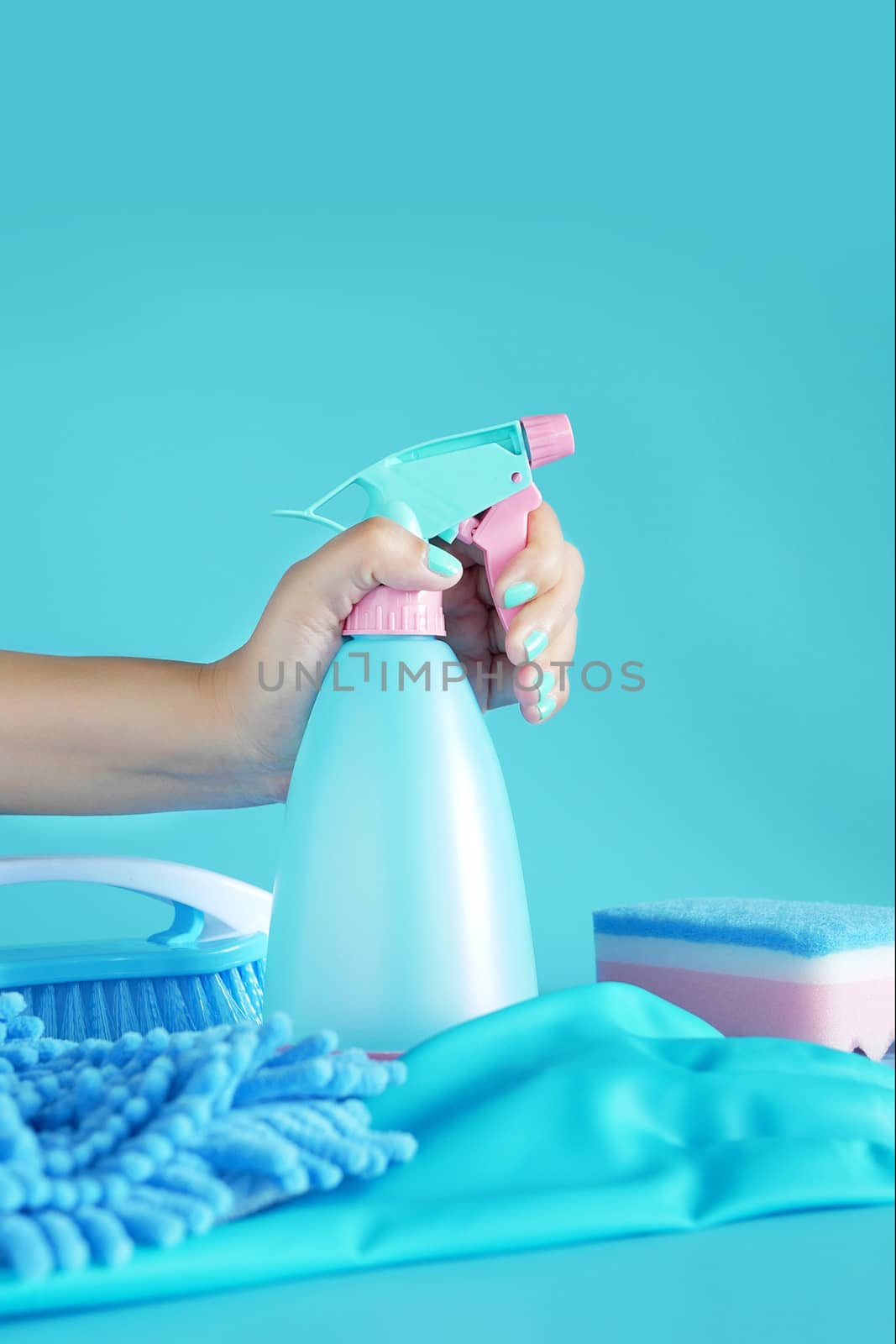 woman hand holding cleaning spray blue plastic bottle detergent isolated on blue background with cleaning tools product supplies