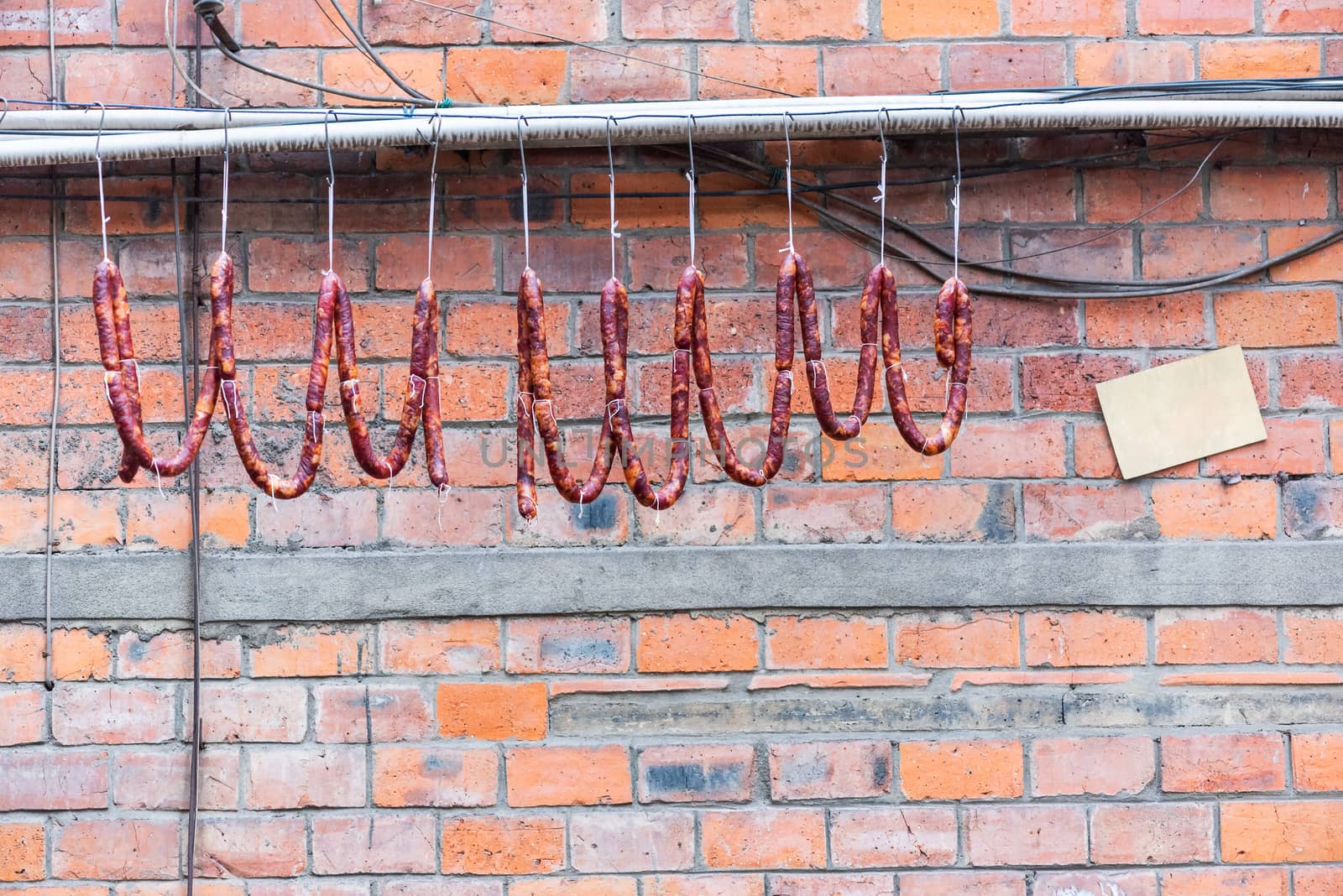 Sausages hanging on a wire against a brick wall, Chengdu, Sichuan province, China