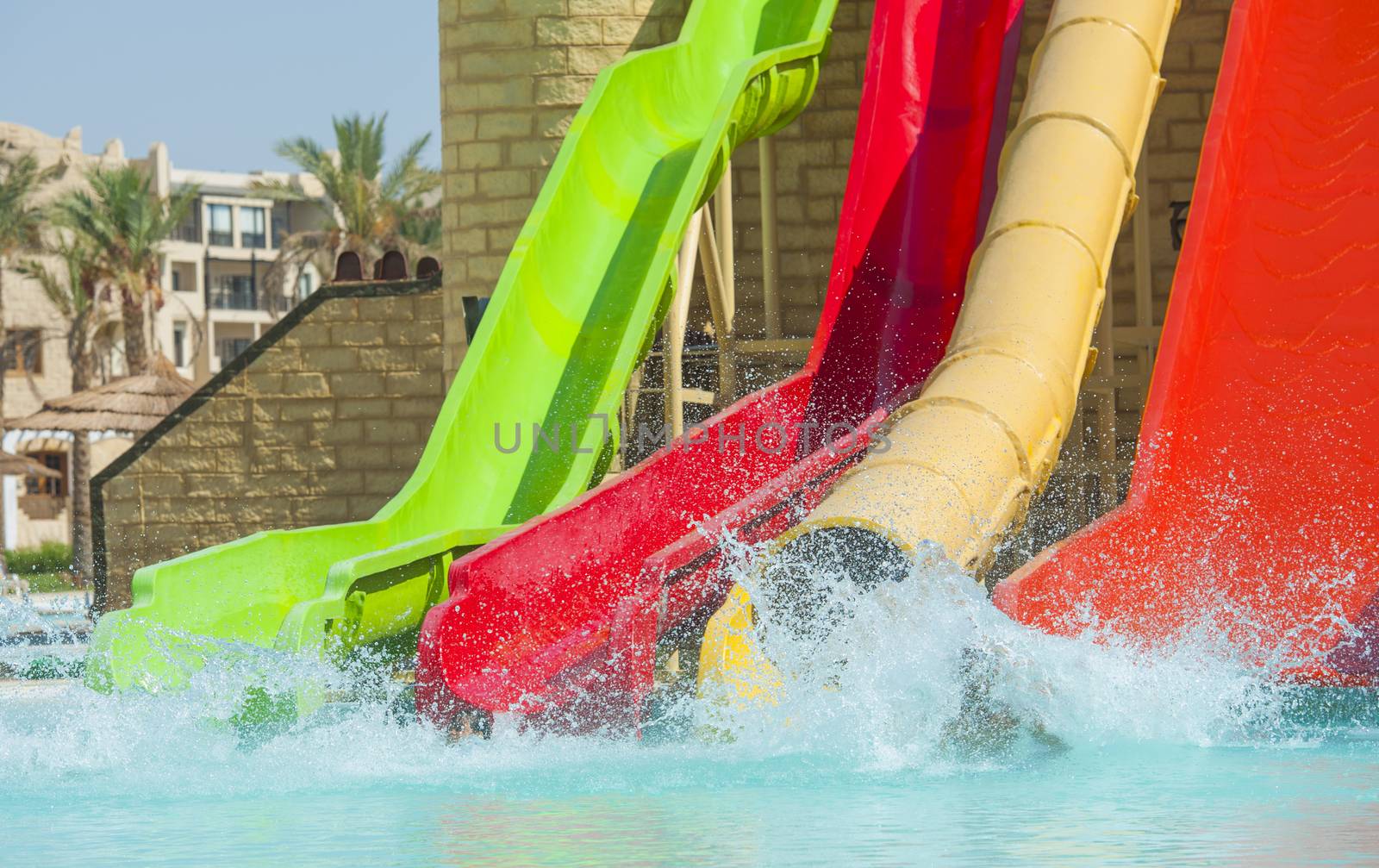 Water slides at a large swimming pool in luxury tropical hotel by paulvinten