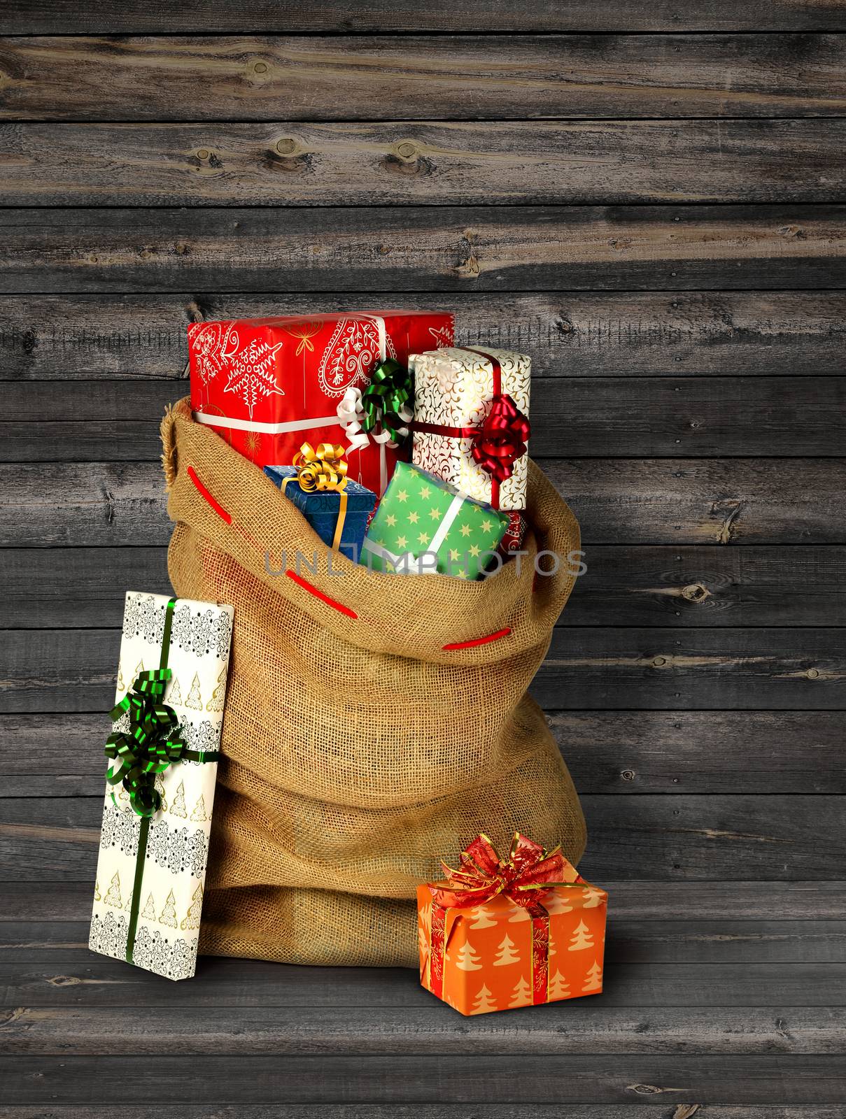 Santas present sack with gift boxes against old grey wooden plank wall