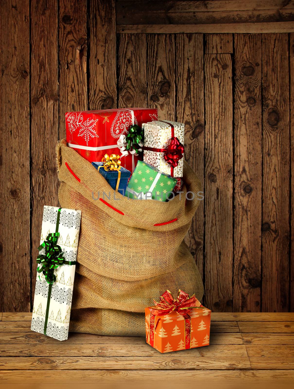 Santas present sack with gift boxes against old rough wooden plank wall