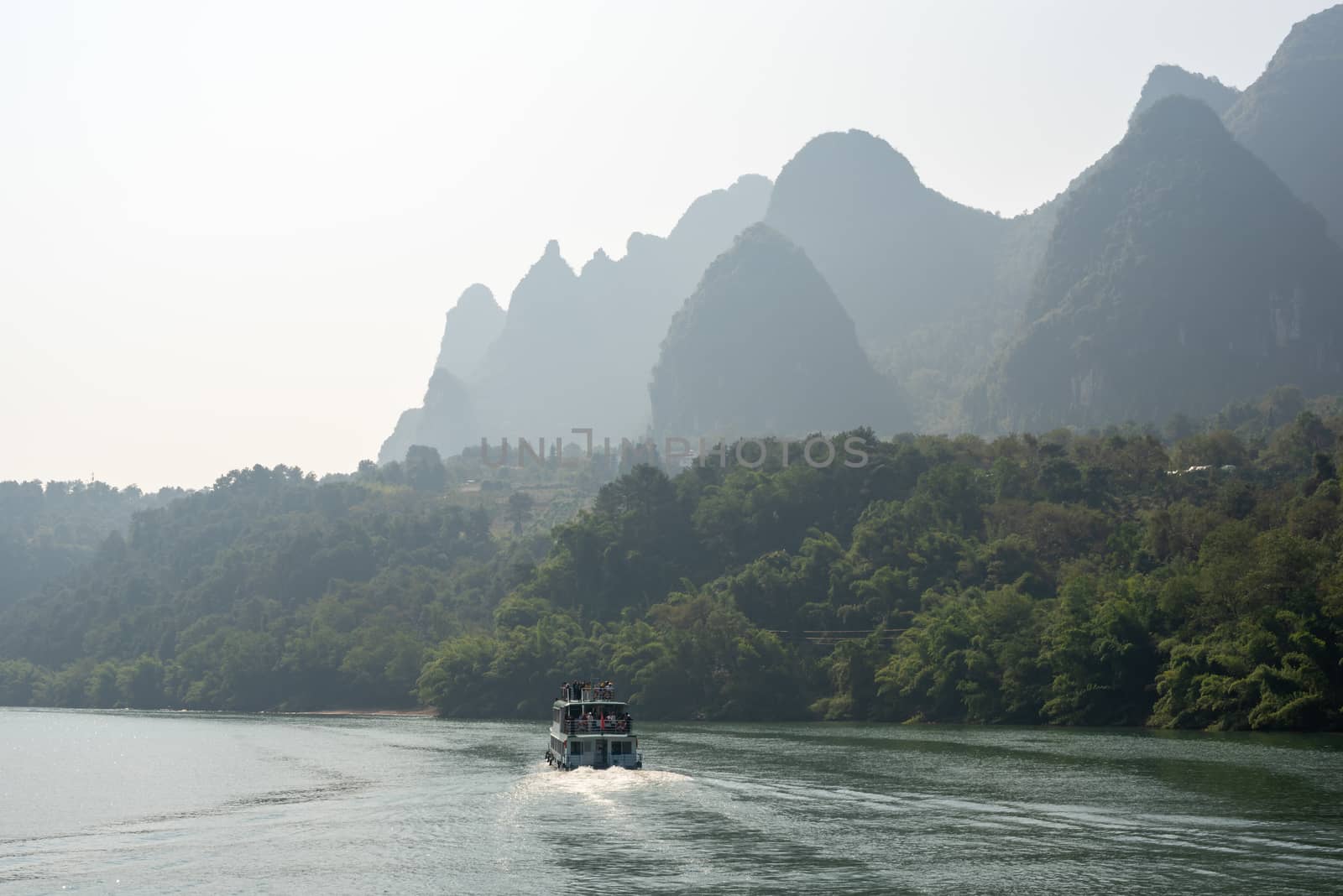 Boat on Li river cruise and karst formation mountain landscape in the fog between Guiling and Yangshuo, Guangxi province, China