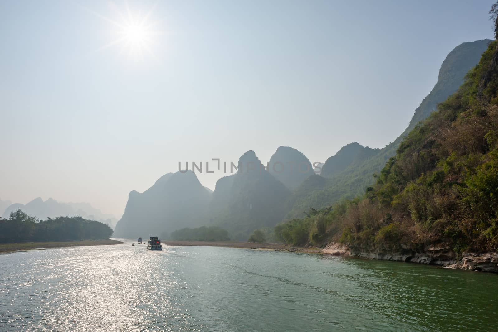 Boat on Li river cruise and karst formation mountain landscape in the fog between Guiling and Yangshuo, Guangxi province, China
