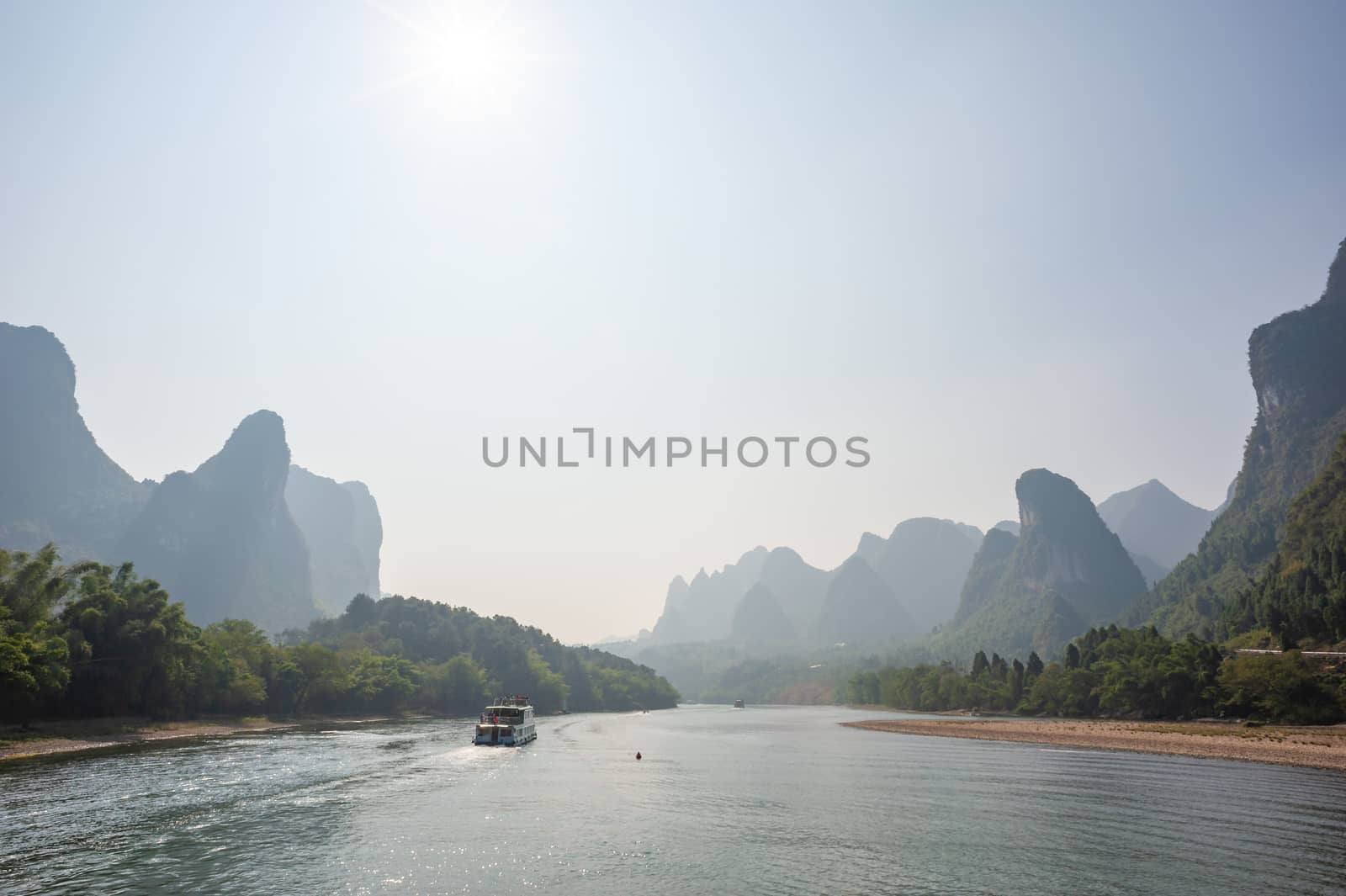 Boat on Li river cruise and karst formation mountain landscape in the fog between Guiling and Yangshuo, Guangxi province, China