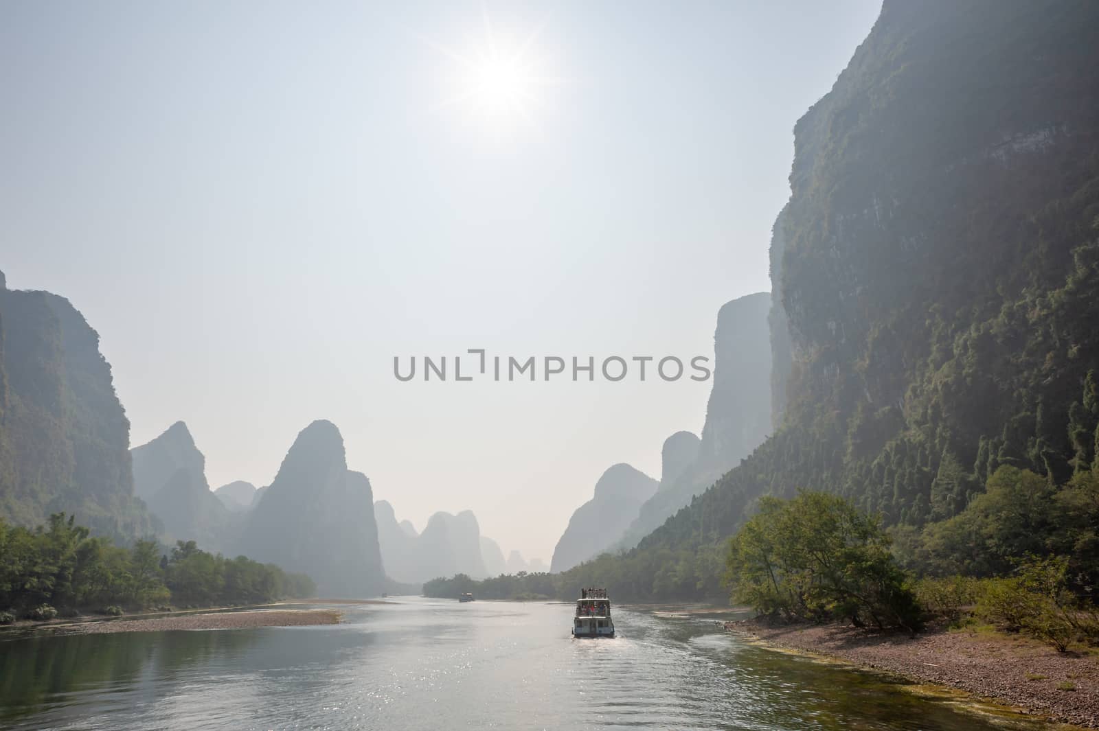 Boat on Li river cruise and karst formation mountain landscape in the fog between Guiling and Yangshuo, Guangxi province, China