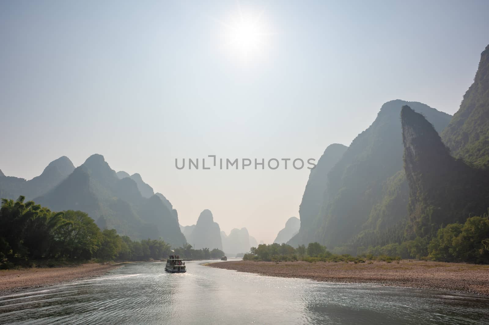 Boat on Li river cruise and karst formation mountain landscape in the fog between Guiling and Yangshuo, Guangxi province, China