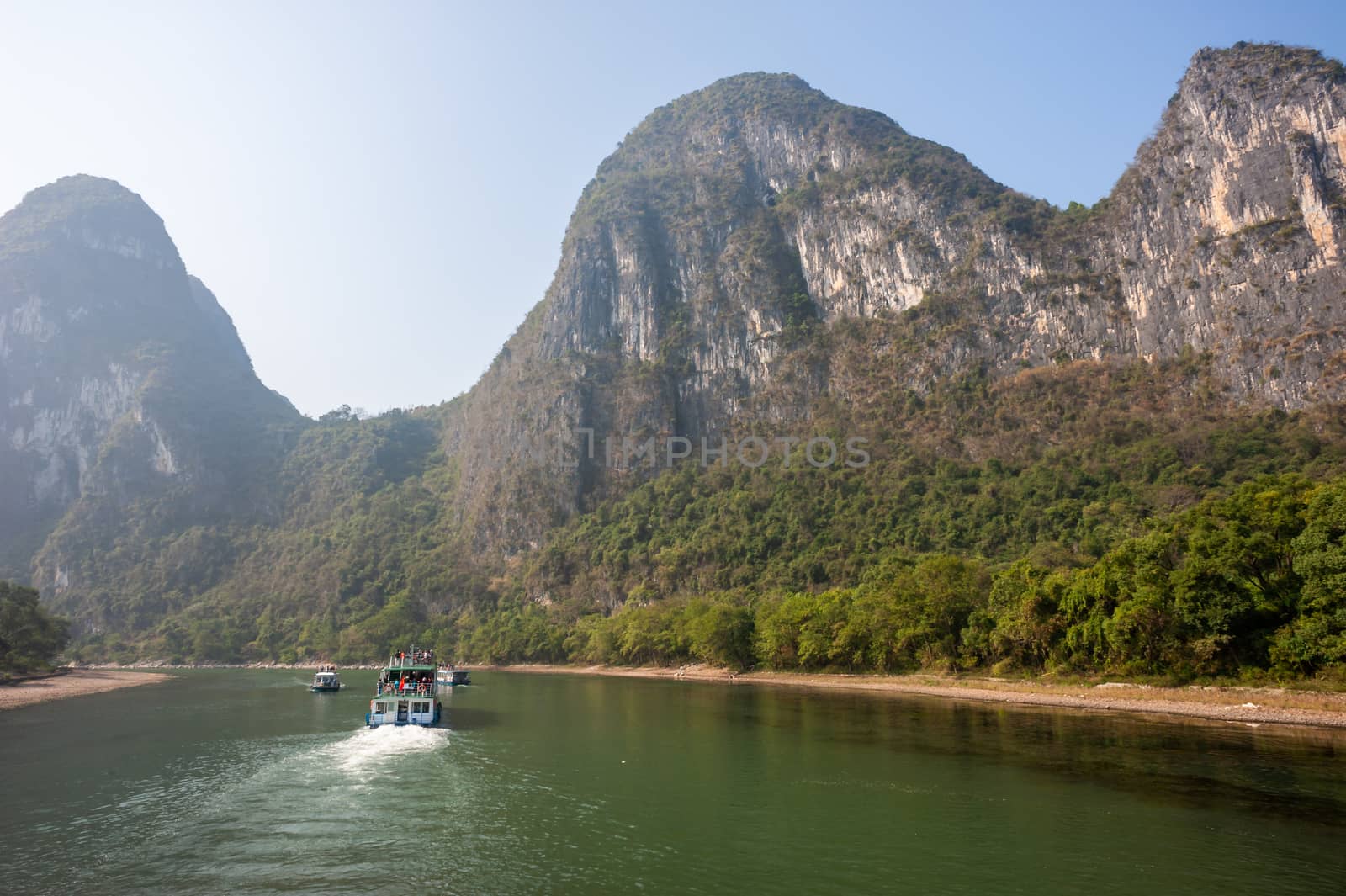 Boat on Li river cruise and karst formation mountain landscape in the fog between Guiling and Yangshuo, Guangxi province, China