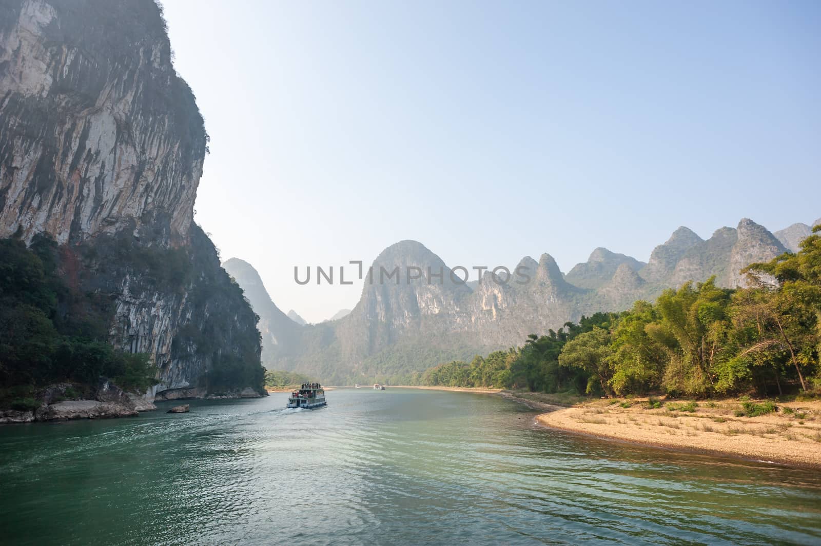 Boat on Li river cruise and karst formation mountain landscape in the fog between Guiling and Yangshuo, Guangxi province, China