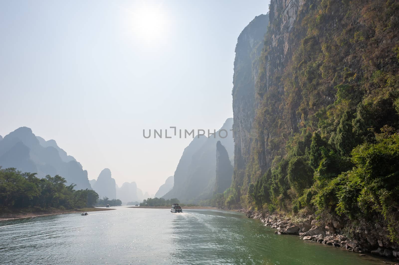 Boat on Li river cruise and karst formation mountain landscape in the fog between Guiling and Yangshuo, Guangxi province, China