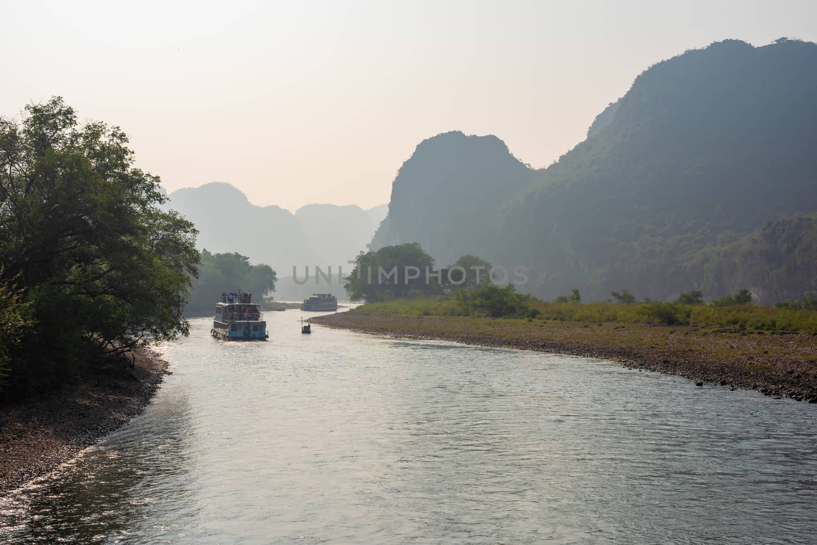 Boat on Li river cruise and karst formation mountain landscape in the fog between Guiling and Yangshuo, Guangxi province, China