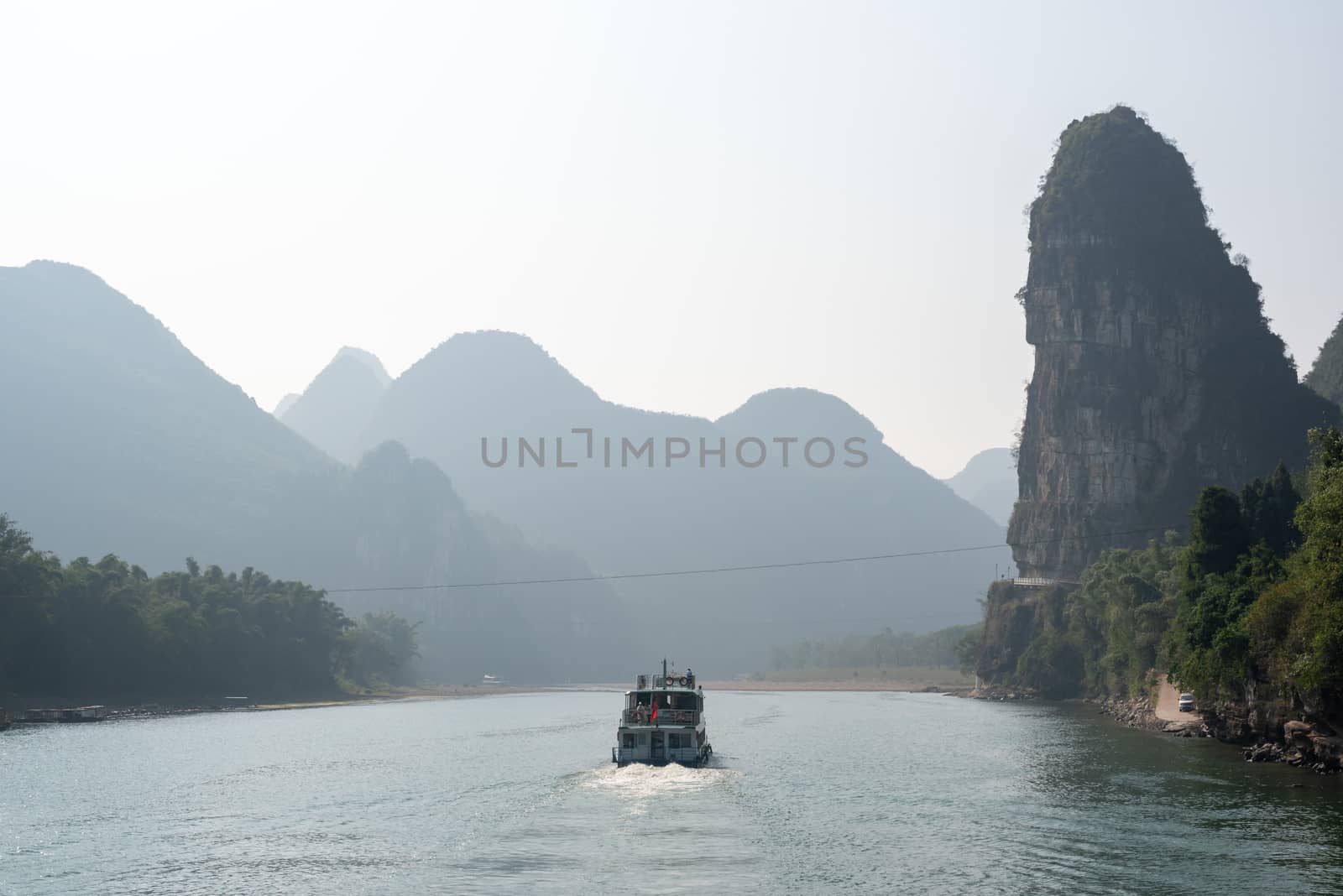 Boat on Li river cruise and karst formation mountain landscape in the fog between Guiling and Yangshuo, Guangxi province, China