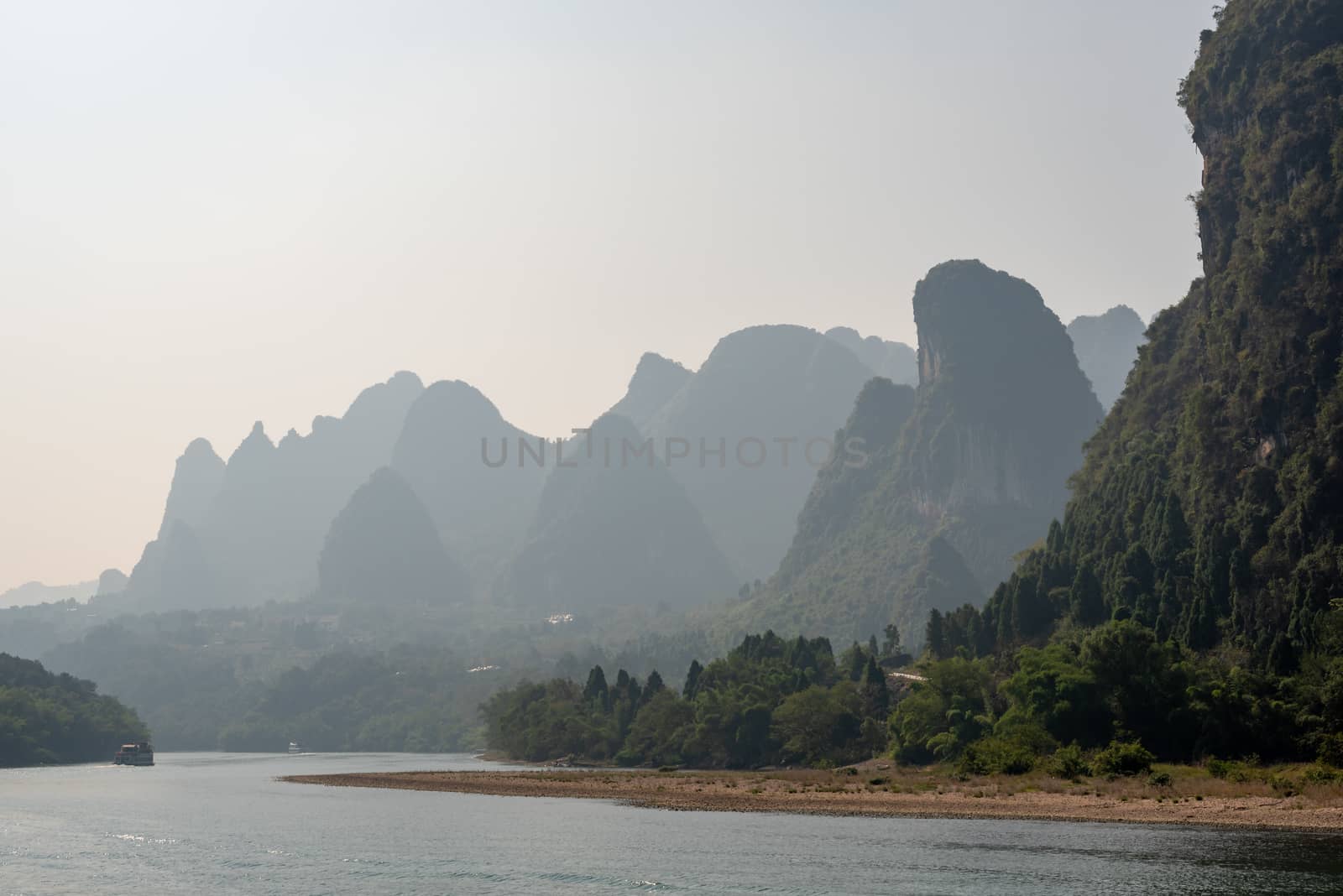 Boat on Li river cruise and karst formation mountain landscape in the fog between Guiling and Yangshuo, Guangxi province, China