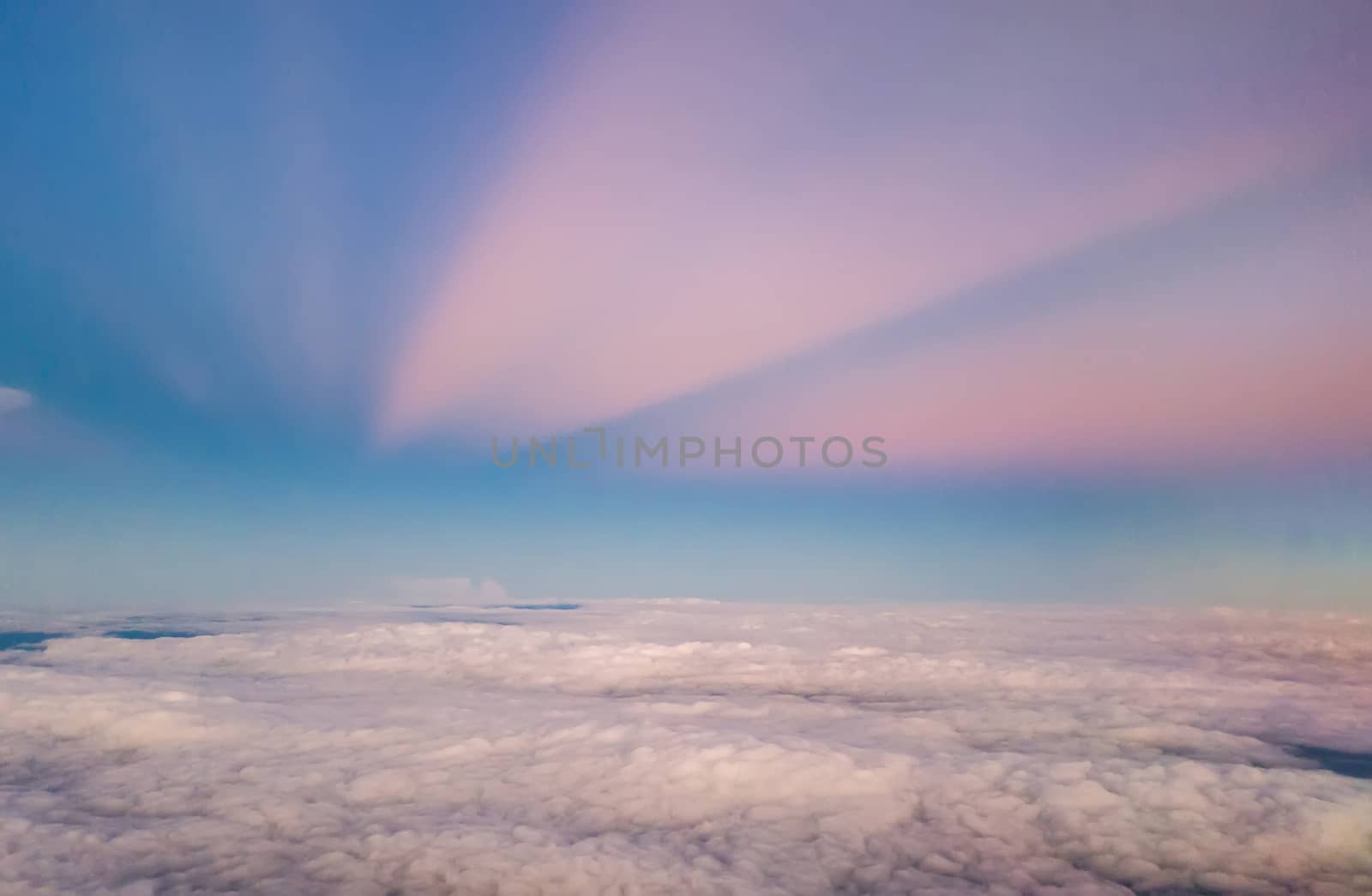 beautiful pastel sky atmosphere over white puffy cloud before sunset as seen through window of airplane, plane window. travel by airplane by asiandelight