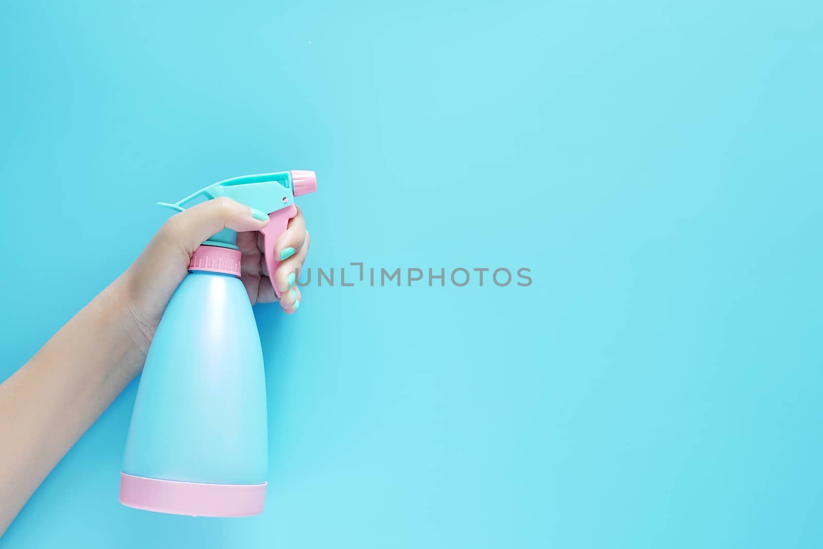 woman hand holding cleaning spray blue plastic bottle detergent isolated on blue background with copy space for text or logo