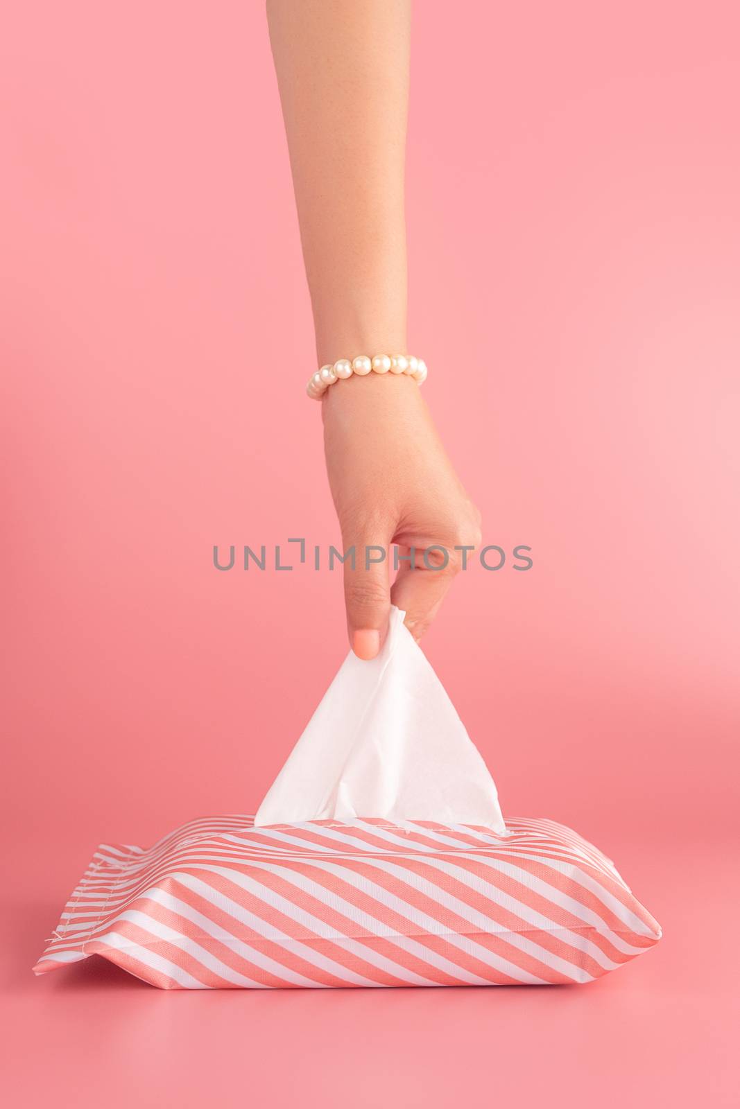 woman pull the tissue paper out of the tissue box isolated on pink background, vertical. sanitation and hygiene facility concept by asiandelight