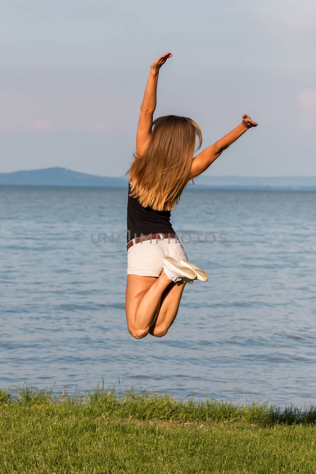Pretty girl jumping near the lake