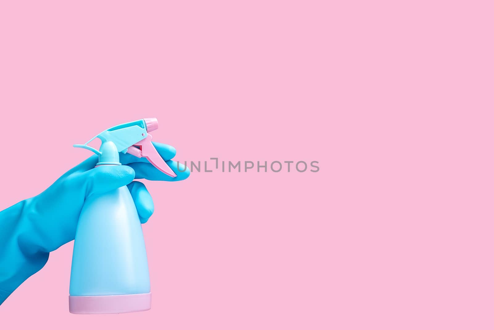 hand in blue rubber glove holding cleaning spray bottle detergent isolated on pink background with copy space for text or logo