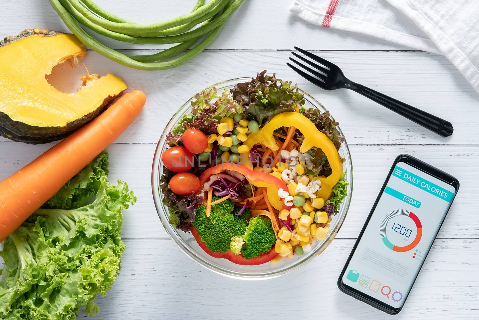 Calories counting , diet , food control and weight loss concept. Calorie counter application on smartphone screen at dining table with salad, fruit juice, bread and vegetable by asiandelight